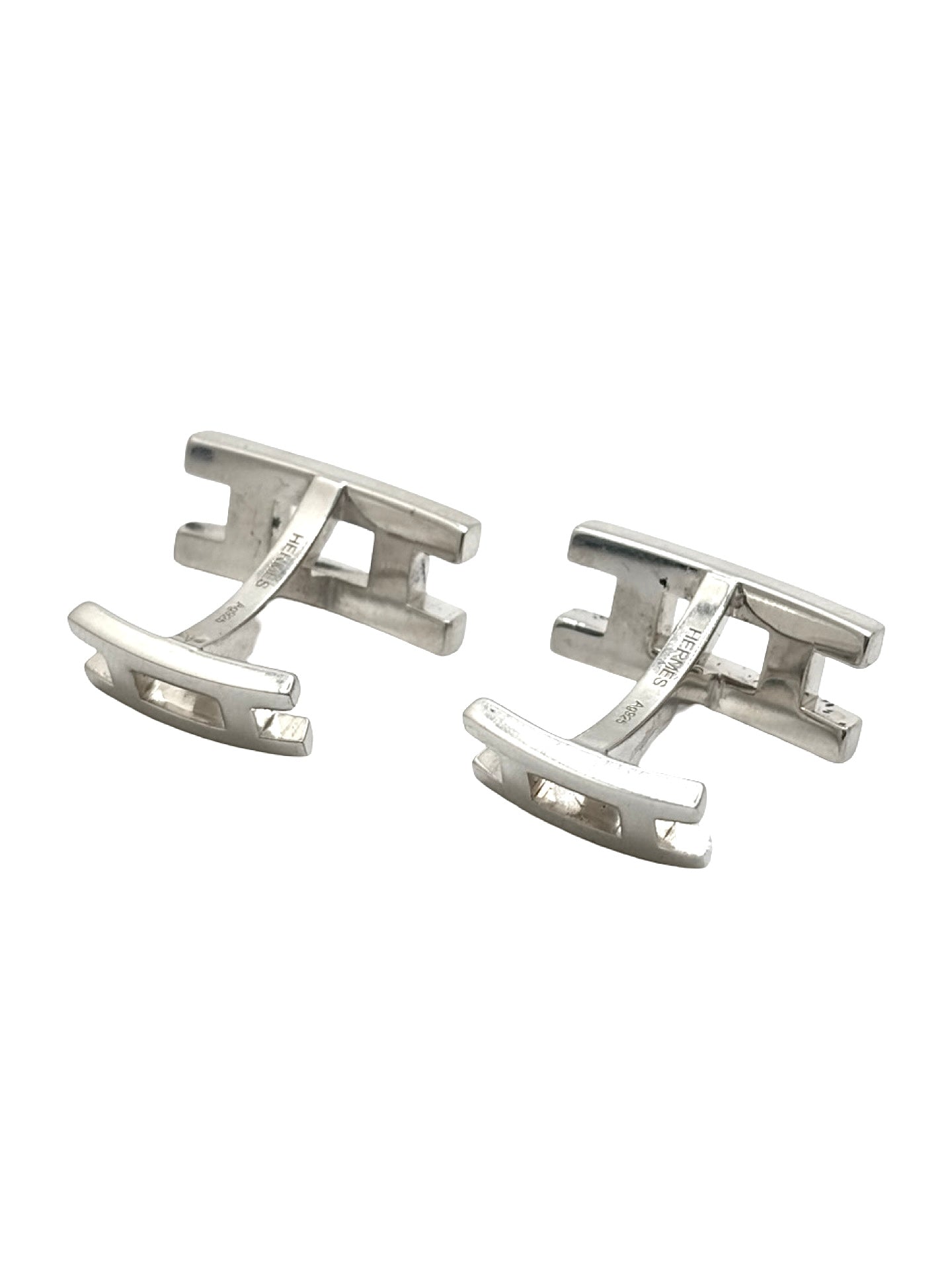 Boutons de manchettes Hermès en argent 925 au style élégant et intemporel. Cette paire raffinée en argent massif séduit par ses finitions soignées et son design sophistiqué caractéristique du savoir-faire Hermès. Accessoires de luxe parfaits pour compléter un costume, une tenue habillée ou une cérémonie. Boutons de manchettes précieux alliant distinction, élégance masculine et qualité joaillière dans un esprit chic et contemporain.