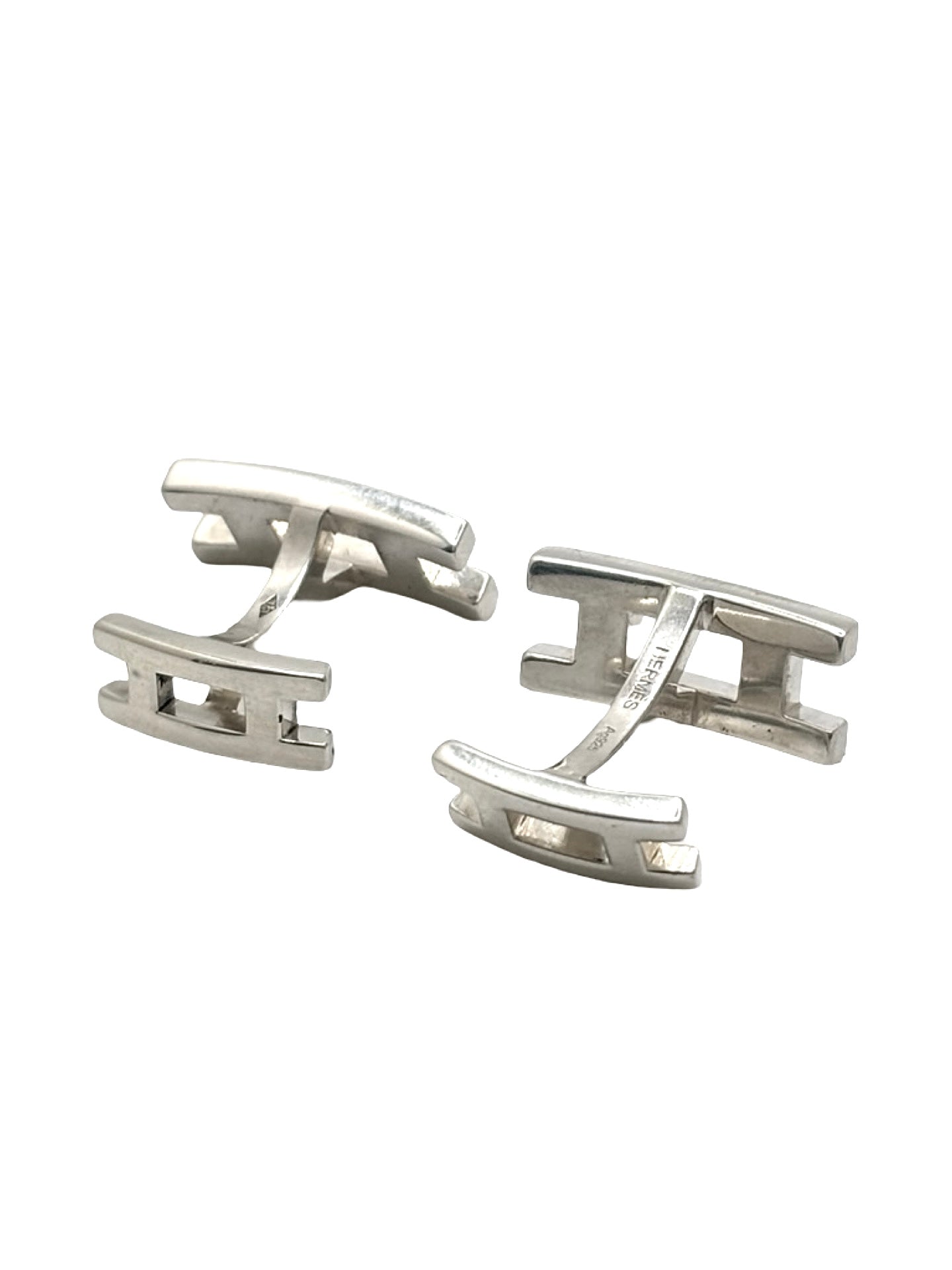 Boutons de manchettes Hermès en argent 925 au style élégant et intemporel. Cette paire raffinée en argent massif séduit par ses finitions soignées et son design sophistiqué caractéristique du savoir-faire Hermès. Accessoires de luxe parfaits pour compléter un costume, une tenue habillée ou une cérémonie. Boutons de manchettes précieux alliant distinction, élégance masculine et qualité joaillière dans un esprit chic et contemporain.