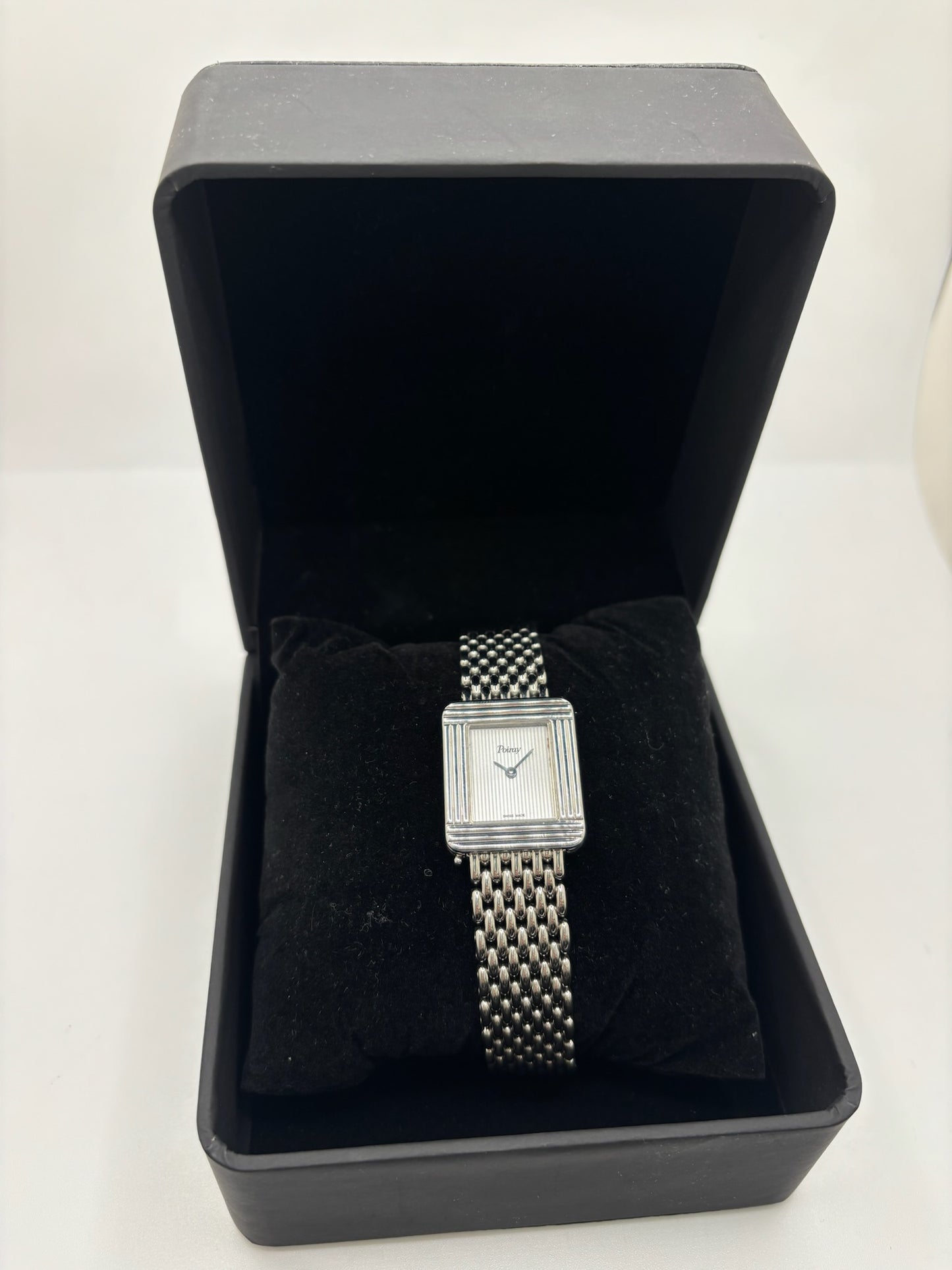 Montre Poiray Ma Première pour femme en acier inoxydable avec boîtier rectangulaire de 22,5 x 26 mm. Cette montre quartz arbore un cadran argenté protégé par un verre saphir et un bracelet en acier à boucle double pliant. Élégante et intemporelle, cette montre de luxe féminine d'occasion séduit par son design emblématique et sa finition raffinée. Modèle iconique de la maison Poiray, idéal pour les amateurs d'horlogerie et de joaillerie française.