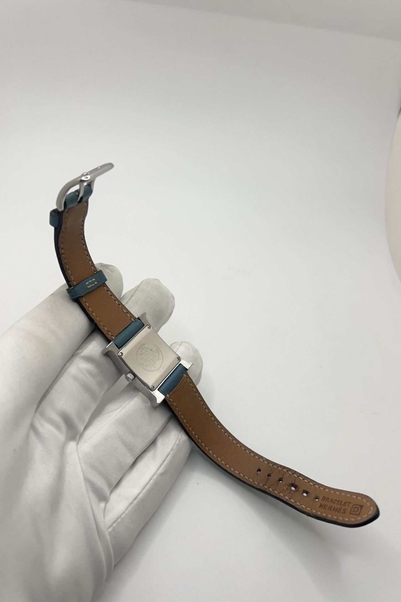 Montre Hermès Heure H HH1.210 en acier avec cadran bleu à chiffres arabes et bracelet cuir Hermès bleu d’origine. Cette montre Hermès femme quartz au design iconique en forme de H incarne l’élégance parisienne et le luxe discret. Modèle Hermès Heure H acier de 21 x 30 mm avec verre saphir, boucle ardillon acier et mouvement quartz fiable. Montre de luxe féminine chic et intemporelle, révisée et livrée avec certificat d’authenticité.