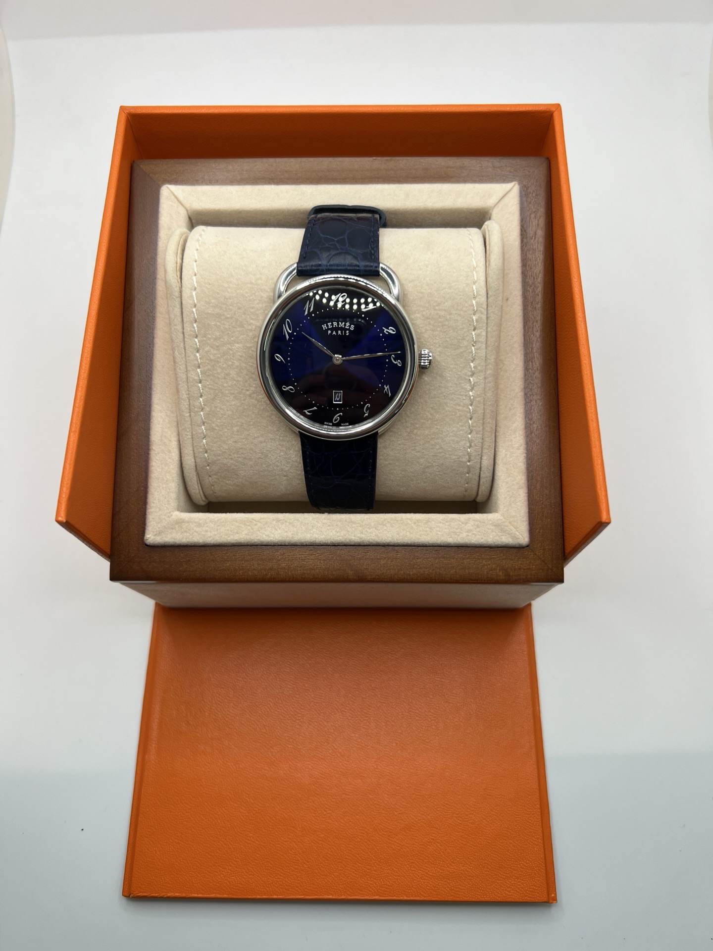 Montre Hermès Arceau grand modèle AR7Q.810 en acier avec cadran blanc épuré, chiffres arabes inclinés signature de la collection Arceau, mouvement quartz précis et bracelet en cuir élégant. Design intemporel et raffiné, idéal pour une tenue chic au quotidien ou une occasion spéciale, alliant savoir-faire horloger et esthétique minimaliste.