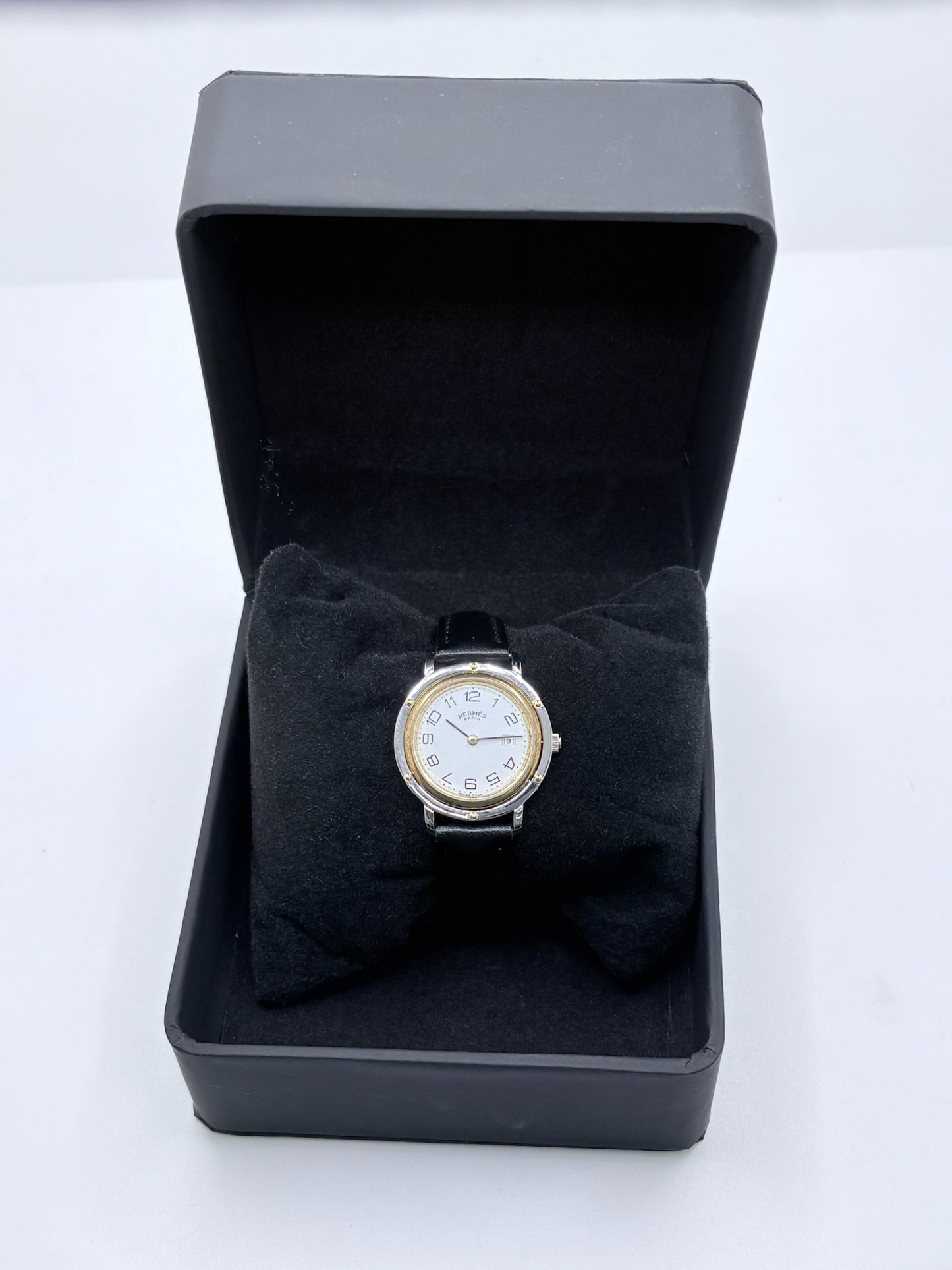 Montre Hermès Clipper pour femme en acier, équipée d’un mouvement à quartz. Son boîtier de 30 mm est associé à une lunette en or jaune, un cadran blanc avec chiffres arabes et un verre saphir. Cette montre Hermès Clipper est montée sur un bracelet en cuir de vache noir avec boucle ardillon en acier. Un modèle élégant et intemporel de la collection Clipper, idéal pour les amateurs de montres de luxe.