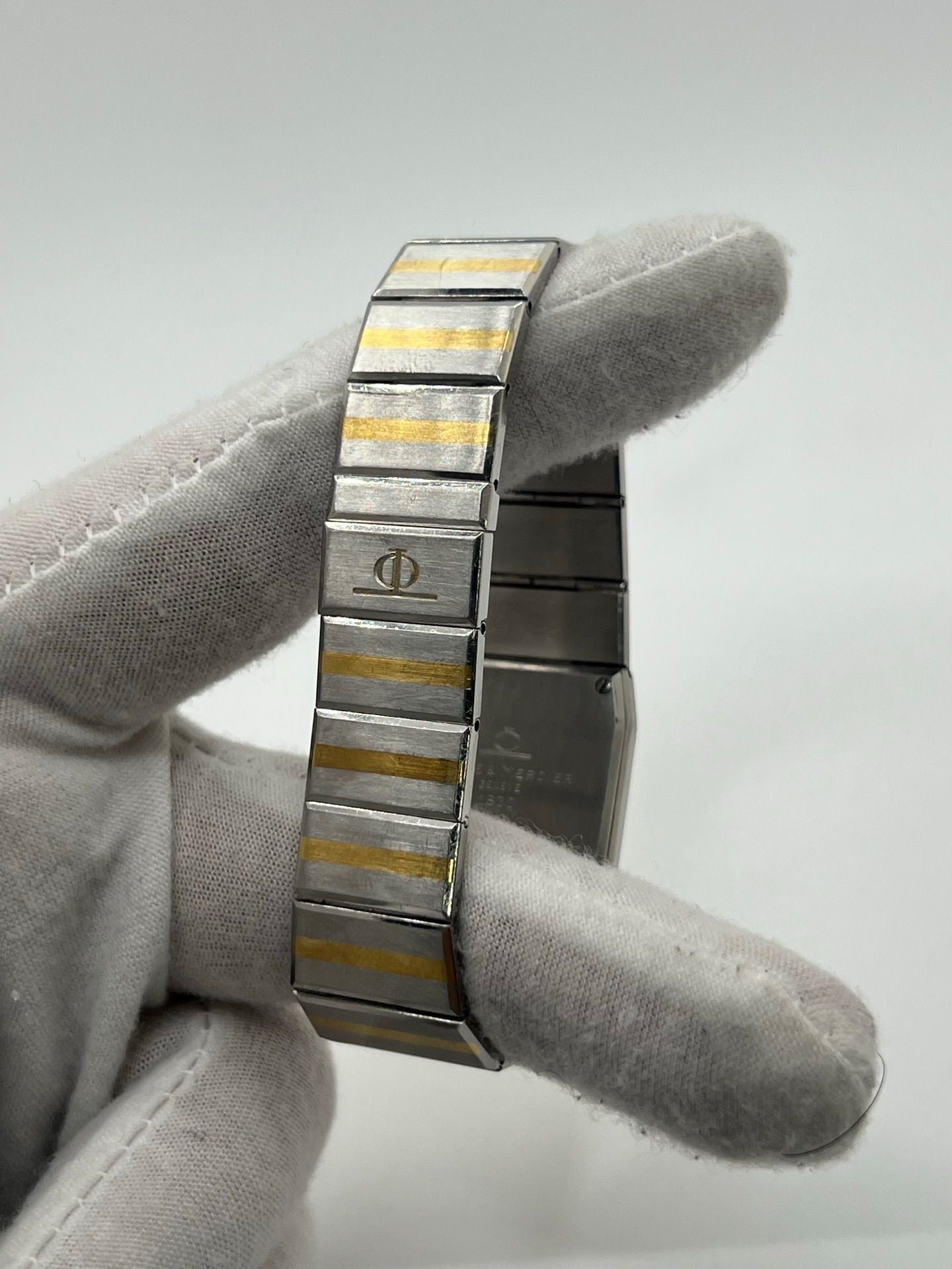 Montre Baume & Mercier Carlo Zebra 5739.038 pour homme/unisexe, mouvement quartz, boîtier acier 25x32 mm, cadran or, verre saphir et bracelet or/acier avec boucle pli. Étanche 10 ATM, d'occasion en bon état, disponible sans coffret ni papiers d'origine. Idéale pour les amateurs de montres de luxe élégantes et intemporelles.