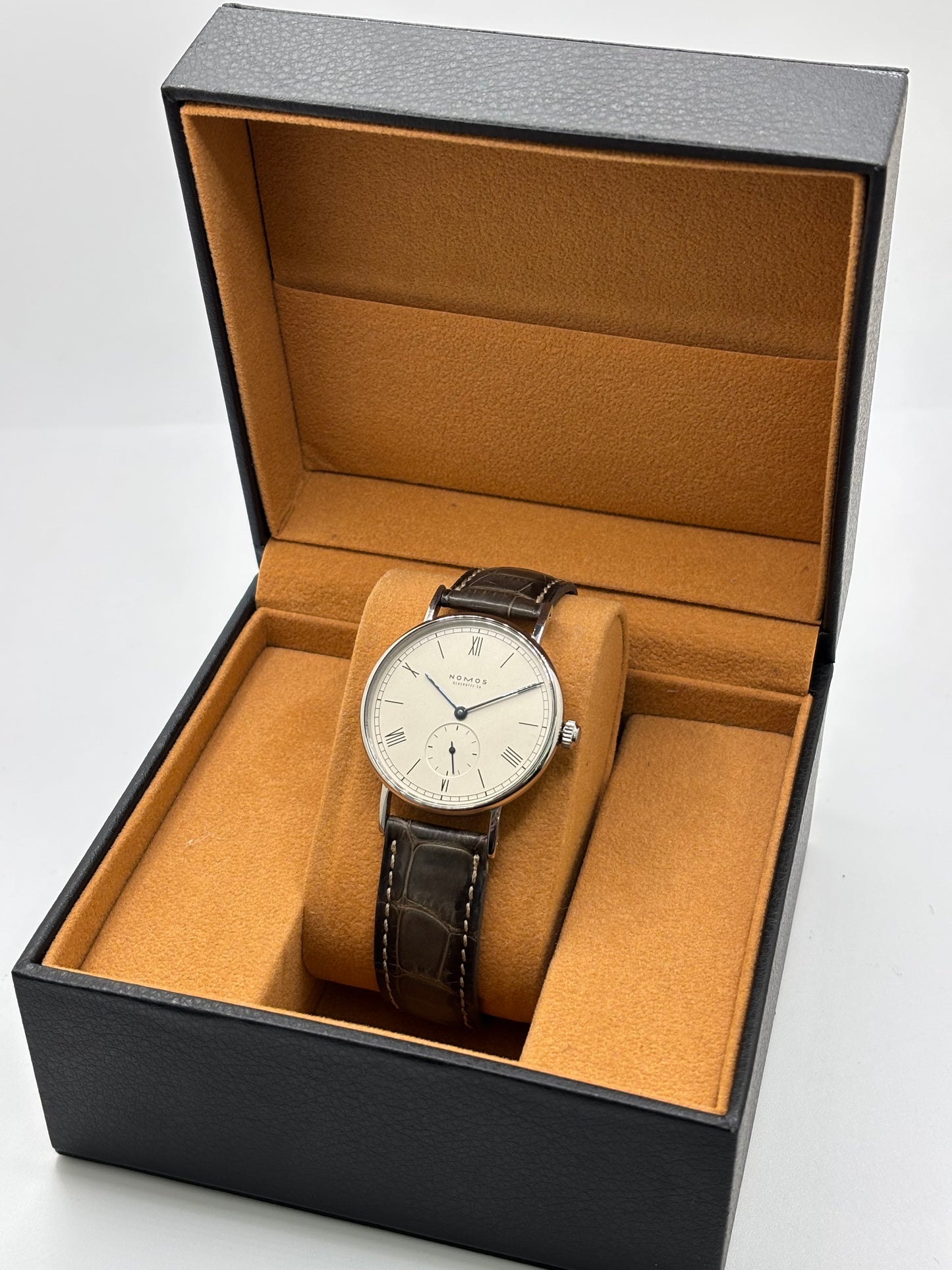 Montre Nomos Glashütte Ludwig 205 en acier avec boîtier de 37,5 mm, mouvement à remontage manuel offrant 43 heures de réserve de marche et cadran blanc à chiffres romains. Équipée d'un verre saphir, d'un bracelet en cuir noir, d'une petite seconde, d'un fond transparent et d'aiguilles en acier bleui, cette montre de luxe d'occasion est en très bon état avec de légères traces d'usure. Un modèle élégant au style intemporel, idéal pour les amateurs d'horlogerie.