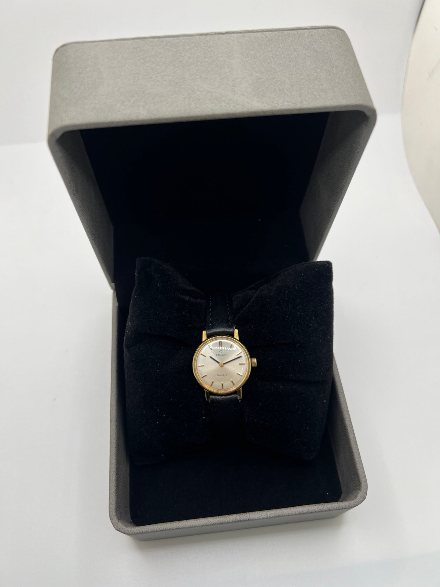 Montre Omega Genève femme vintage de 1972 en plaqué or, avec mouvement à remontage manuel. Boîtier de 23 mm au cadran doré orné de pierres précieuses et verre en plastique. Bracelet en cuir noir avec boucle en acier. Modèle élégant et intemporel, en bon état avec traces d’usure visibles. Révisée en avril 2026, vendue sans coffret ni papiers, disponible en stock en France.