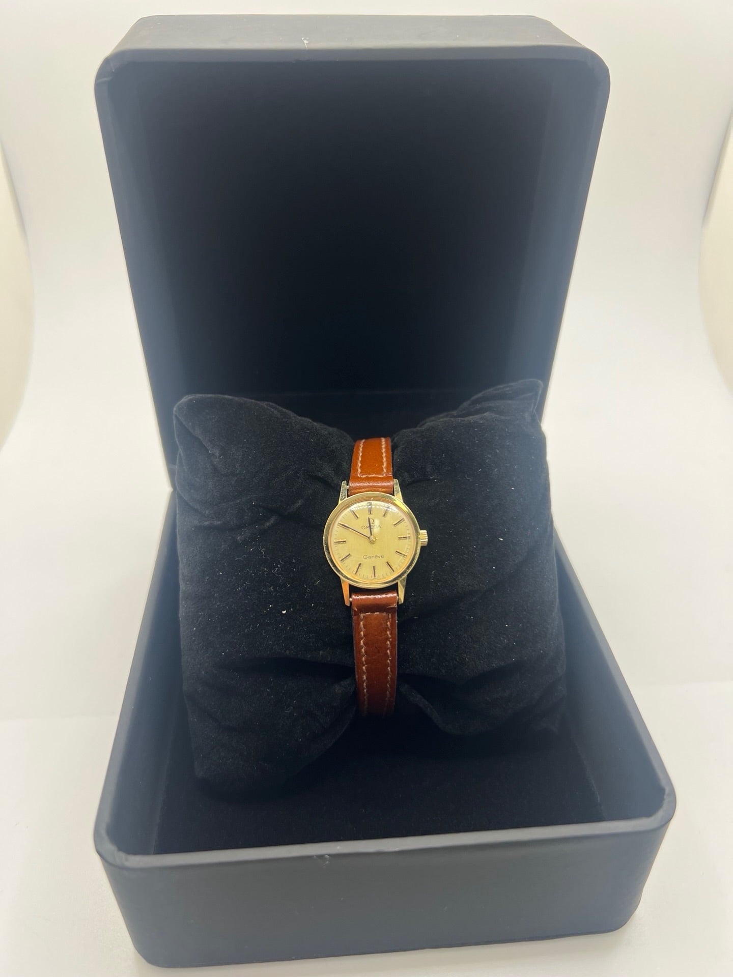 Montre Omega Genève Lady en acier avec boîtier plaqué or de 20 mm, cadran or à index bâtons, mouvement calibre 560, bracelet en cuir brun avec boucle acier. Vintage de 1978, d'occasion en bon état avec traces d'usure visibles. Verre plexiglas, modèle élégant pour femme, idéal pour collection ou usage quotidien. Livrée sans coffret ni papiers d'origine, disponible en stock à Paris.