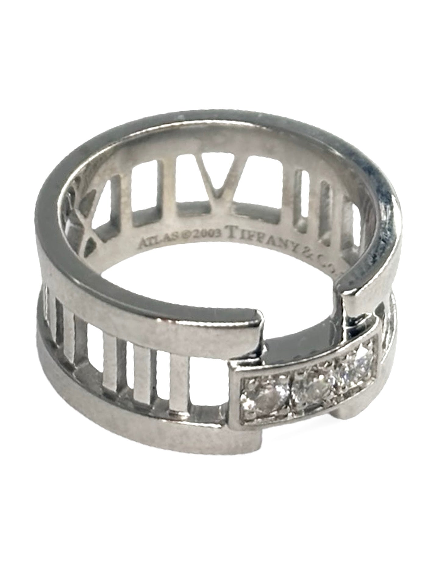 Bague Atlas ring en or blanc signée Tiffany & Co., sertie de diamants totalisant 0,15 carat. Son design graphique emblématique, inspiré des chiffres romains, allie modernité et élégance intemporelle. Un bijou raffiné et lumineux, idéal pour sublimer la main au quotidien ou marquer une occasion spéciale avec une pièce iconique de la joaillerie de luxe.