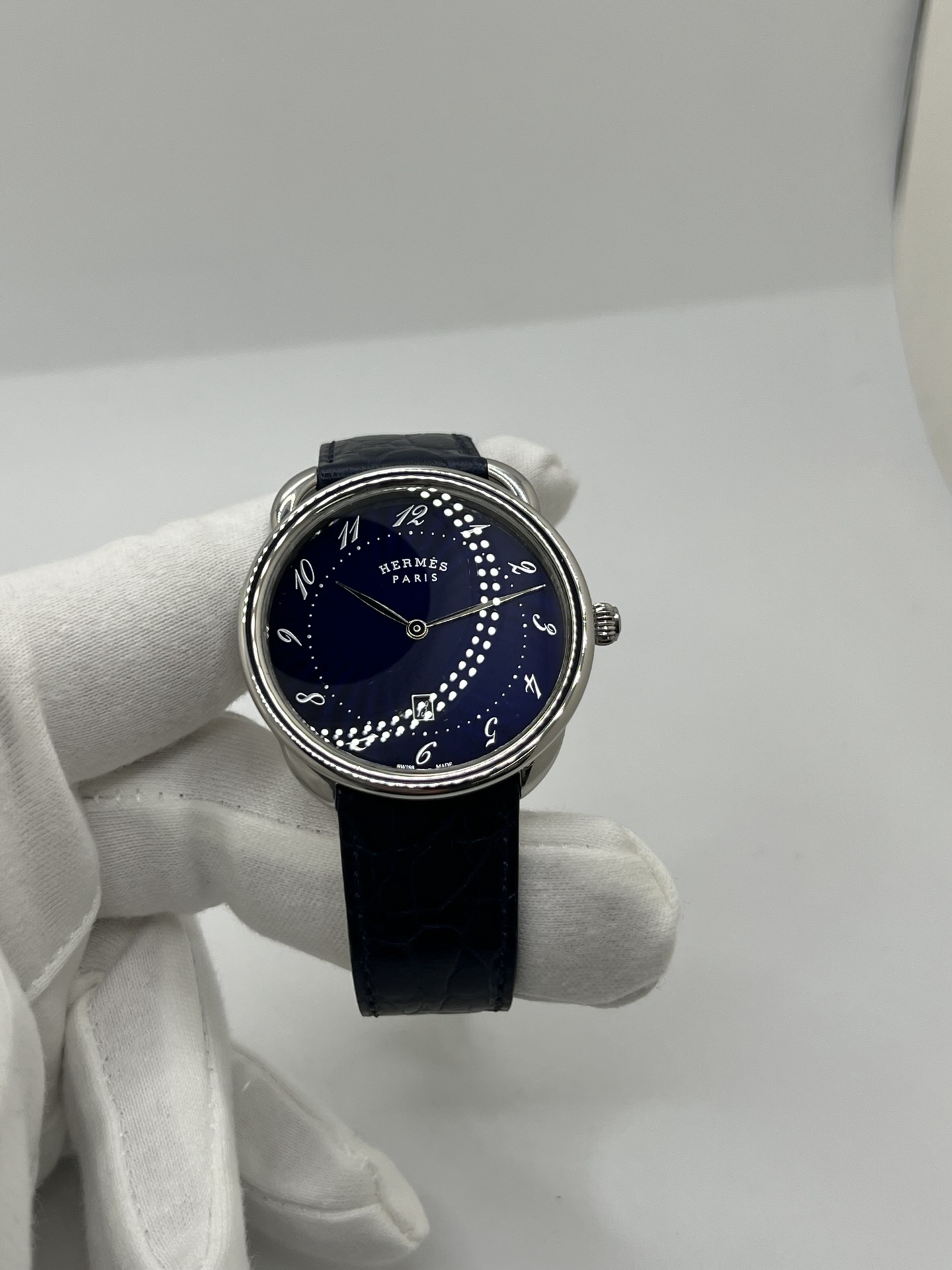 Montre Hermès Arceau grand modèle AR7Q.810 en acier avec cadran blanc épuré, chiffres arabes inclinés signature de la collection Arceau, mouvement quartz précis et bracelet en cuir élégant. Design intemporel et raffiné, idéal pour une tenue chic au quotidien ou une occasion spéciale, alliant savoir-faire horloger et esthétique minimaliste.