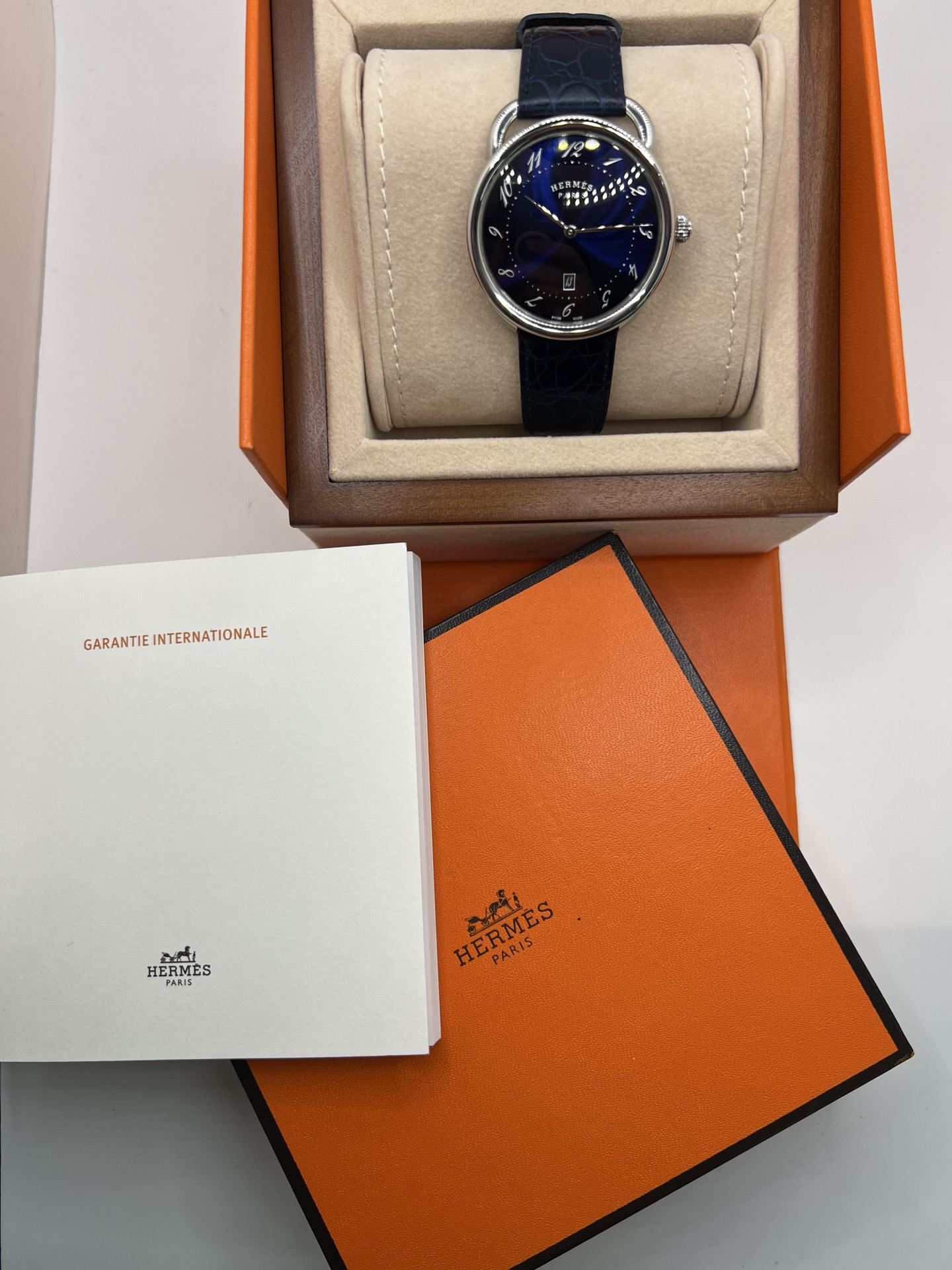 Montre Hermès Arceau grand modèle AR7Q.810 en acier avec cadran blanc épuré, chiffres arabes inclinés signature de la collection Arceau, mouvement quartz précis et bracelet en cuir élégant. Design intemporel et raffiné, idéal pour une tenue chic au quotidien ou une occasion spéciale, alliant savoir-faire horloger et esthétique minimaliste.