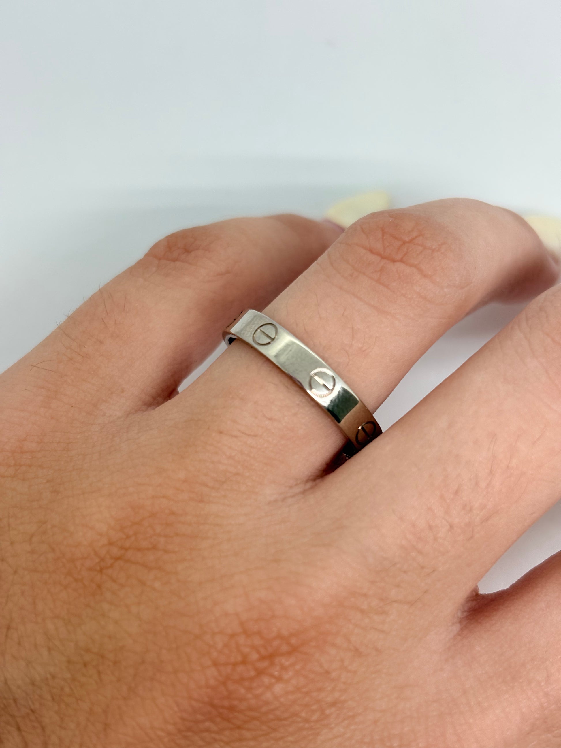 Bague Cartier Love petit modèle en or blanc 18K, un bijou iconique de la maison Cartier reconnaissable à son design intemporel inspiré d’un bracelet vissé. Cette bague en or blanc 18 carats séduit par ses lignes élégantes et raffinées. Le petit modèle offre une silhouette délicate, idéale portée seule ou associée à d’autres bagues. Une pièce emblématique de joaillerie, parfaite pour un style chic et contemporain.