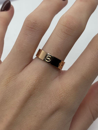 Bague Love en or rose 18 carats, modèle moyen, au design iconique et intemporel. Cet anneau emblématique se distingue par ses motifs gravés évoquant l’attachement et l’élégance. Sa finition polie met en valeur la chaleur de l’or rose et assure un rendu raffiné. Bijou de caractère, idéal à porter seul ou en accumulation, parfait pour un usage quotidien ou comme symbole fort à offrir.