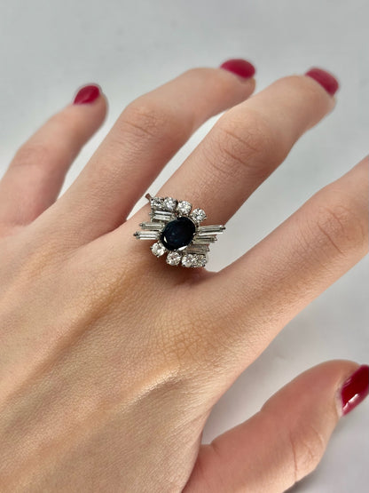 Bague en or blanc 18 carats sertie d’un saphir central de 1,5 carat sublimé par un entourage de diamants totalisant 1 carat. Ce bijou raffiné associe l’intensité du bleu du saphir à l’éclat des diamants, offrant une allure élégante et intemporelle. Idéale pour une occasion précieuse, elle incarne luxe, brillance et savoir-faire joaillier.