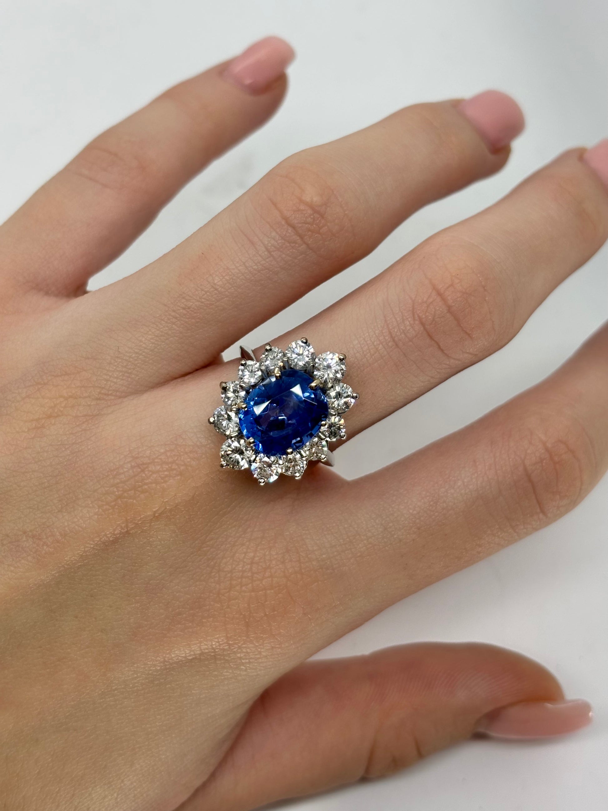 Bague marguerite en or blanc 18K sertie d’un saphir birman non chauffé de 5,58 carats, certifié par le GRS (janvier 2026). Sa couleur bleu profond, intense et veloutée illustre la rareté des saphirs naturels de Birmanie. Il est sublimé par un entourage de diamants naturels totalisant environ 2 carats. Une pièce exceptionnelle, alliant élégance intemporelle, caractère et valeur patrimoniale.