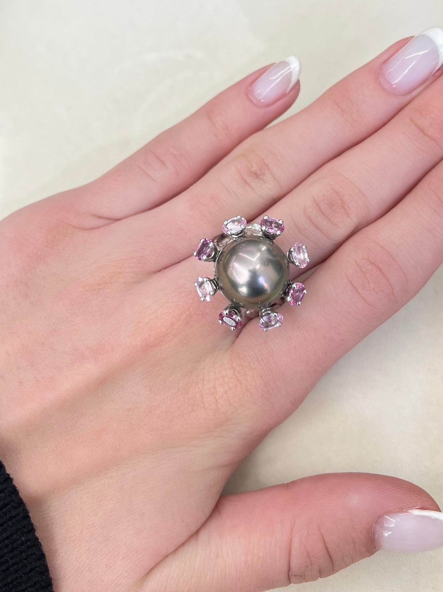 Découvrez cette élégante bague en or blanc signée Roland Schad, un bijou unique mettant en valeur une perle de Tahiti d'exception et des saphirs roses naturels. Ce design raffiné allie parfaitement la douceur de la perle de Tahiti à la brillance des pierres précieuses, offrant ainsi une pièce intemporelle pour les amateurs de joaillerie fine. Idéale pour ceux qui recherchent une bague sophistiquée et originale.