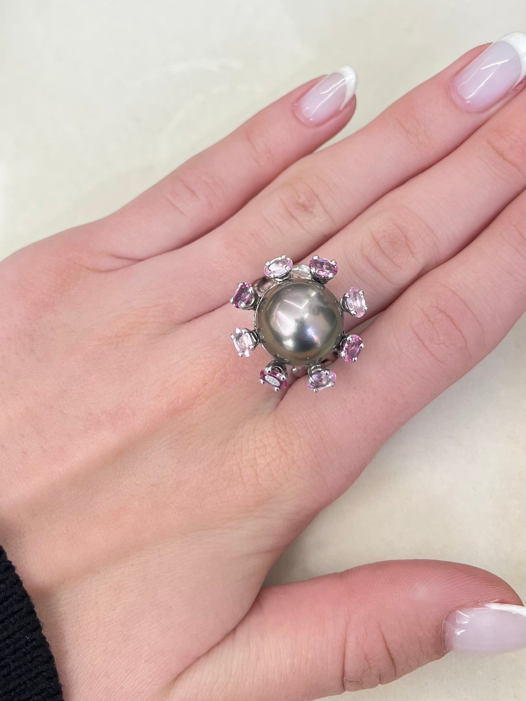 Découvrez cette élégante bague en or blanc signée Roland Schad, un bijou unique mettant en valeur une perle de Tahiti d'exception et des saphirs roses naturels. Ce design raffiné allie parfaitement la douceur de la perle de Tahiti à la brillance des pierres précieuses, offrant ainsi une pièce intemporelle pour les amateurs de joaillerie fine. Idéale pour ceux qui recherchent une bague sophistiquée et originale.