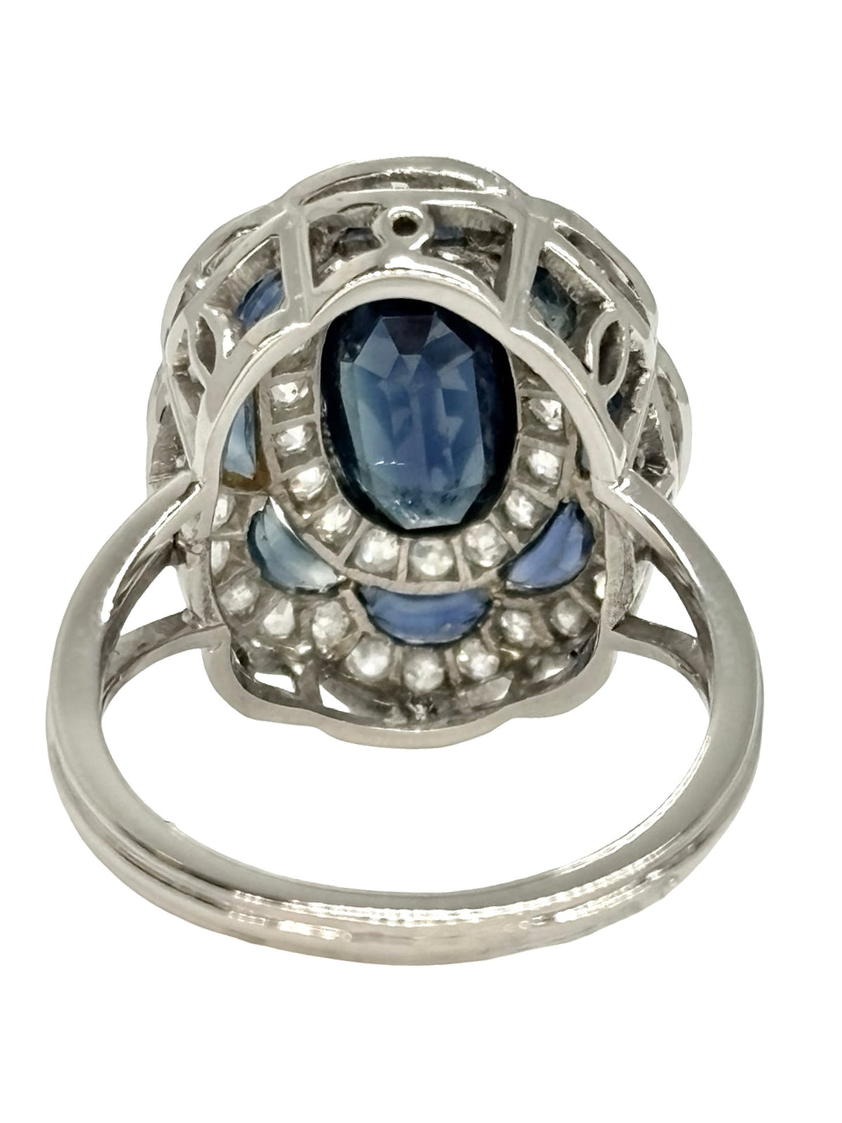 Bague ancienne en or blanc 18K (750 millièmes), sertie d’un saphir naturel central ovale d’environ 2 carats et de petits saphirs naturels en demi-lune. Des diamants naturels de taille ancienne complètent cette pièce de joaillerie pour un poids total d’environ 0,25 carat. Cette bague vintage en or blanc séduit par son élégance intemporelle, ses pierres précieuses et son charme raffiné.