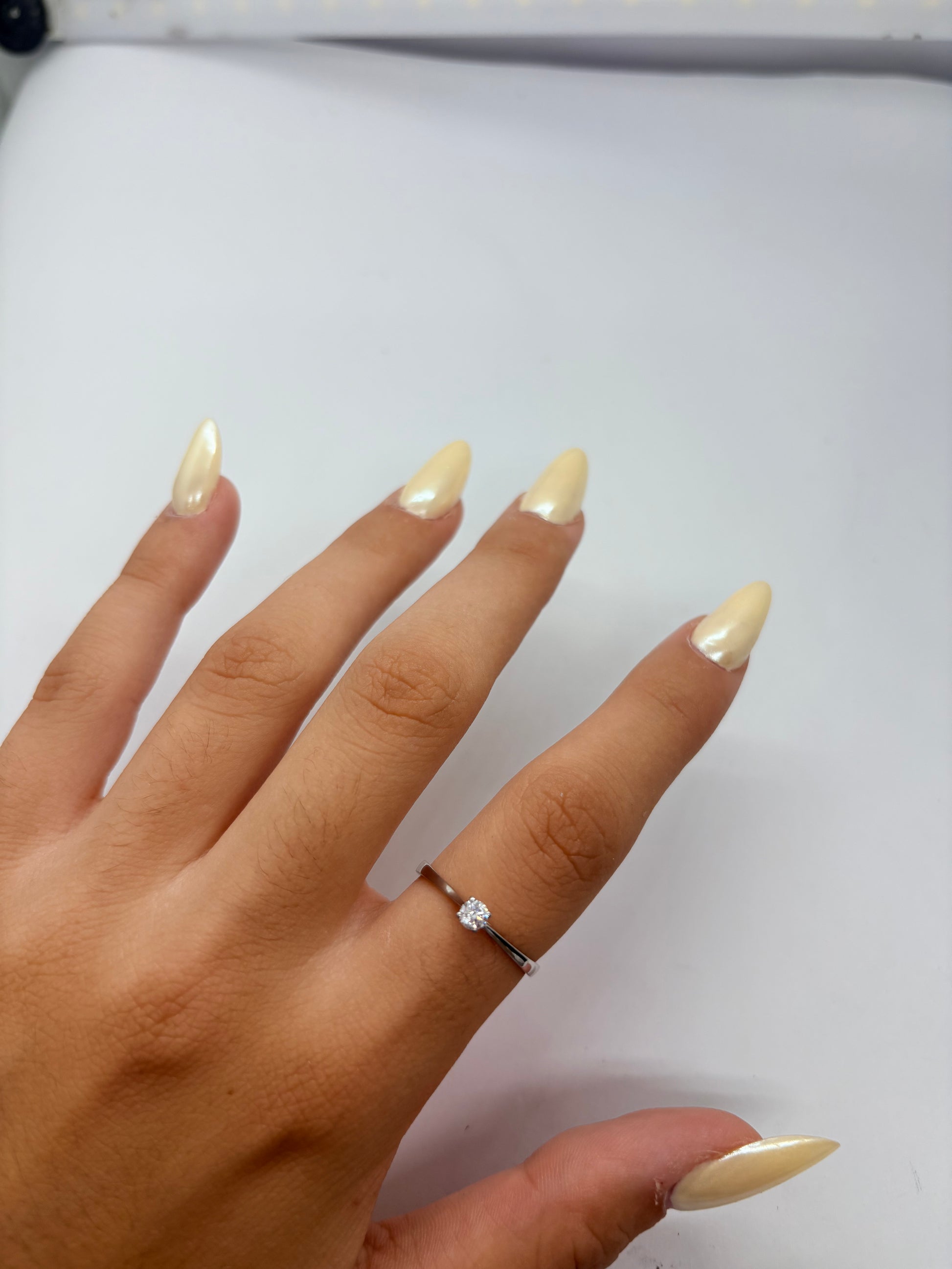 Bague solitaire en or blanc 18K (750/1000) sublimée par un diamant naturel de 0,16 carat. Ce bijou de mariage au design intemporel et élégant met en valeur la brillance d'une pierre centrale étincelante sur une monture fine en or blanc raffinée. Idéale comme bague de fiançailles ou cadeau d'anniversaire précieux pour femme, ce solitaire diamant 0,16 ct incarne le savoir-faire de la joaillerie fine. Un anneau d'exception moderne et lumineux pour marquer un moment inoubliable avec élégance.