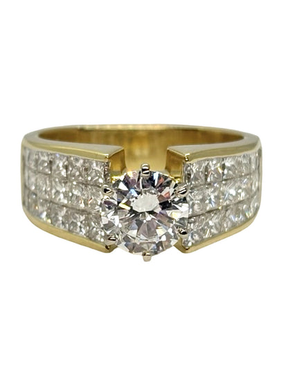 Bague solitaire en or jaune 18K (750 millièmes), sertie de diamants naturels pour un poids total de 3,10 carats. Cette bague en or jaune 18 carats met en valeur un élégant diamant central accompagné de pierres précieuses, offrant un éclat remarquable et une belle présence au doigt. Une création joaillière raffinée et intemporelle, idéale pour celles et ceux à la recherche d’une bague solitaire en or jaune ornée de diamants.