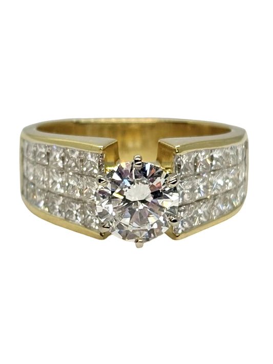 Bague solitaire en or jaune 18K (750 millièmes), sertie de diamants naturels pour un poids total de 3,10 carats. Cette bague en or jaune 18 carats met en valeur un élégant diamant central accompagné de pierres précieuses, offrant un éclat remarquable et une belle présence au doigt. Une création joaillière raffinée et intemporelle, idéale pour celles et ceux à la recherche d’une bague solitaire en or jaune ornée de diamants.
