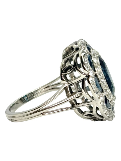 Bague ancienne en or blanc 18K (750 millièmes), sertie d’un saphir naturel central ovale d’environ 2 carats et de petits saphirs naturels en demi-lune. Des diamants naturels de taille ancienne complètent cette pièce de joaillerie pour un poids total d’environ 0,25 carat. Cette bague vintage en or blanc séduit par son élégance intemporelle, ses pierres précieuses et son charme raffiné.