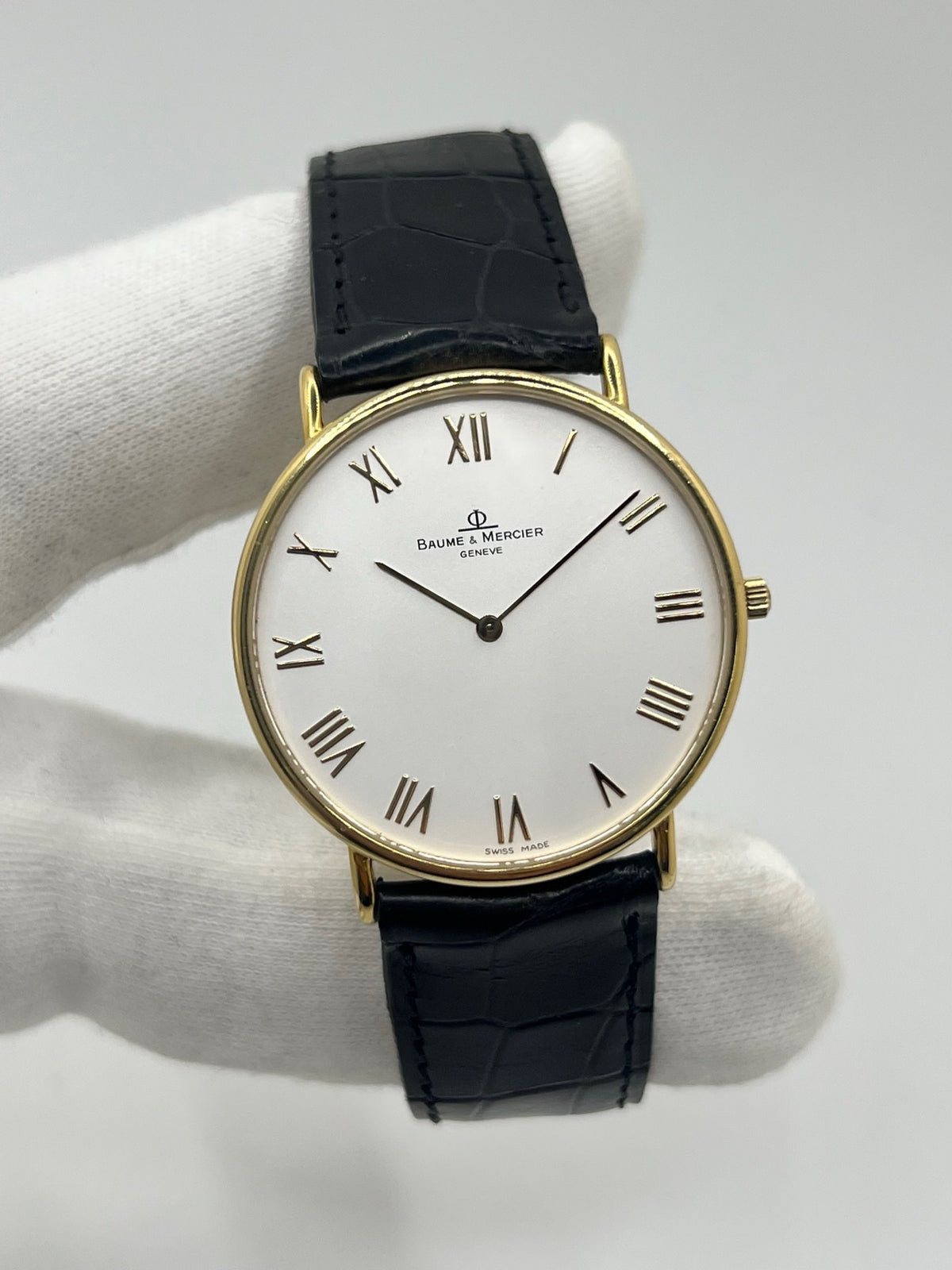 Montre Baume & Mercier Classima 15172A en or jaune, équipée d’un mouvement à quartz et d’un boîtier de 33 mm. Son cadran blanc à chiffres romains apporte une allure élégante et intemporelle, tandis que le verre saphir assure sa protection. Ce modèle est monté sur un bracelet noir en cuir de crocodile avec boucle ardillon en acier. Une montre raffinée, idéale pour une tenue chic et élégante, en très bon état.