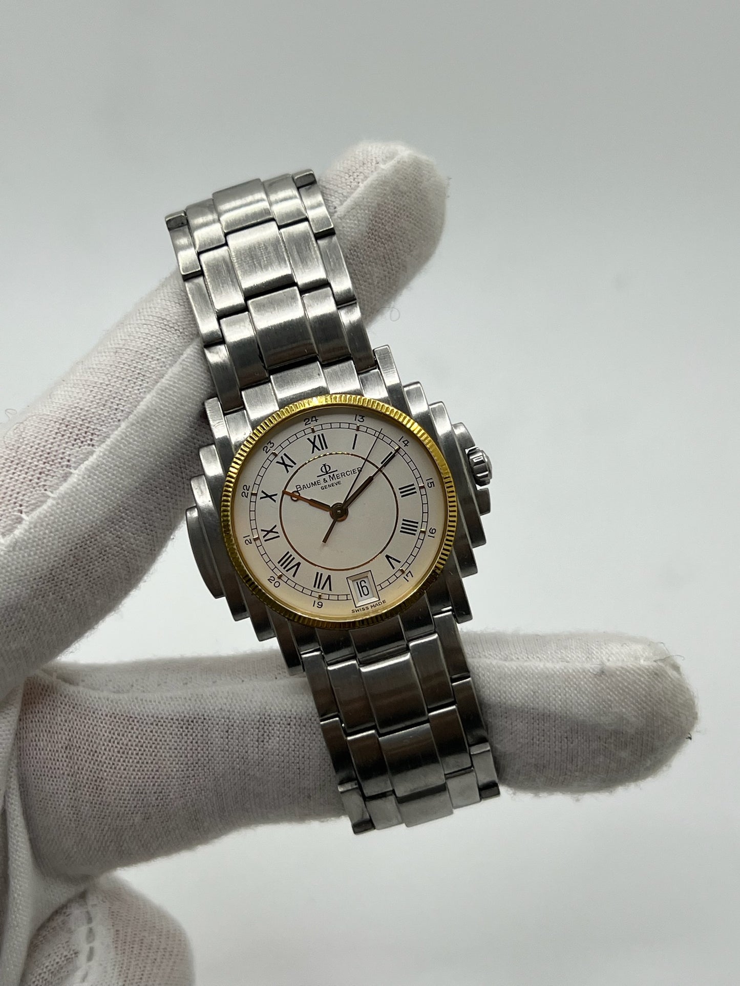 Montre Baume & Mercier 5136.018.3 pour homme/unisexe, boîtier 34 mm en or et acier, cadran blanc à chiffres romains, mouvement quartz précis. Verre saphir résistant aux rayures, bracelet en acier avec boucle double plis. Fonction date. Montre d’occasion en très bon état avec papiers d’origine, élégante et intemporelle.