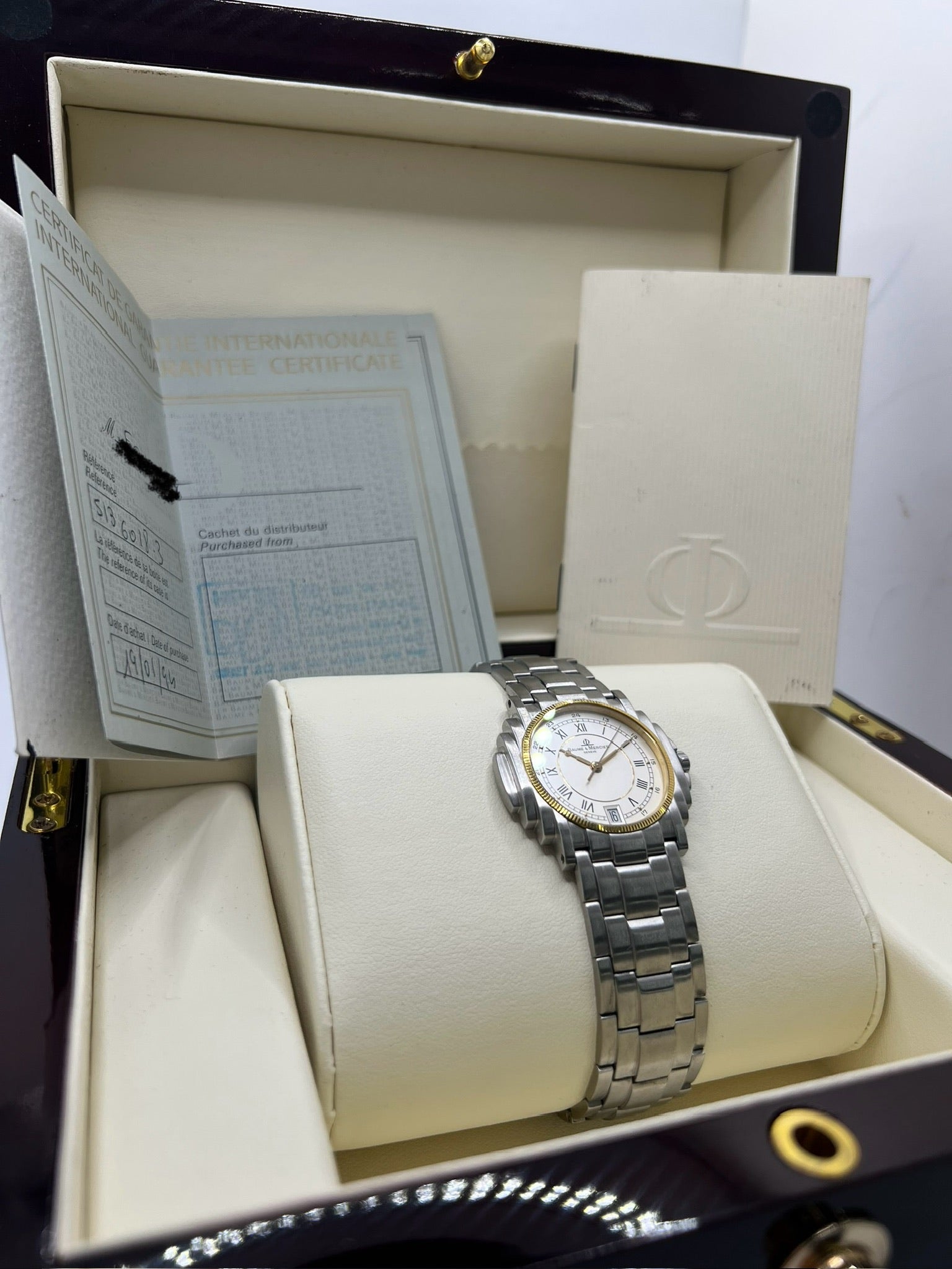 Montre Baume & Mercier 5136.018.3 pour homme/unisexe, boîtier 34 mm en or et acier, cadran blanc à chiffres romains, mouvement quartz précis. Verre saphir résistant aux rayures, bracelet en acier avec boucle double plis. Fonction date. Montre d’occasion en très bon état avec papiers d’origine, élégante et intemporelle.