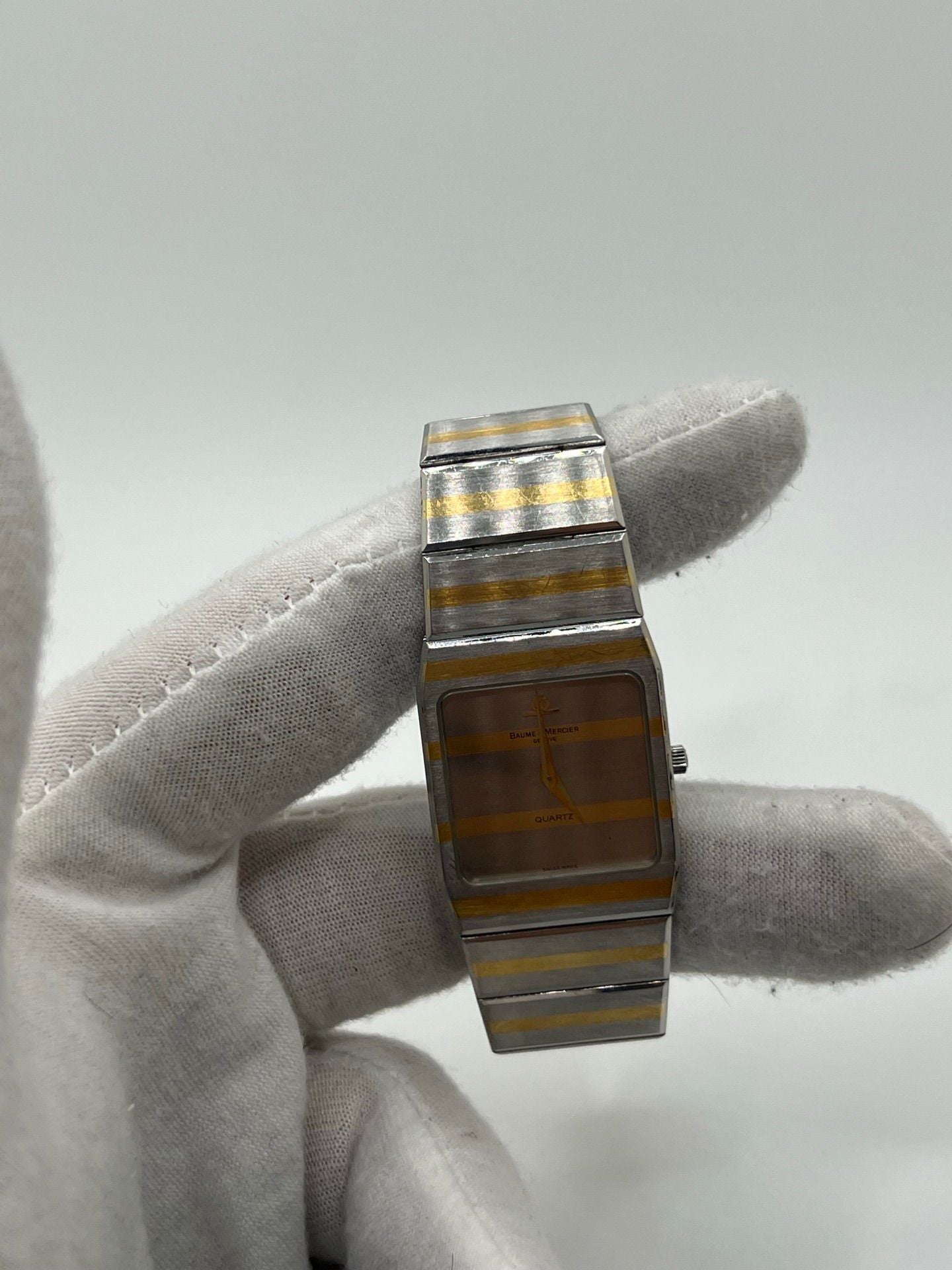 Montre Baume & Mercier Carlo Zebra 5739.038 pour homme/unisexe, mouvement quartz, boîtier acier 25x32 mm, cadran or, verre saphir et bracelet or/acier avec boucle pli. Étanche 10 ATM, d'occasion en bon état, disponible sans coffret ni papiers d'origine. Idéale pour les amateurs de montres de luxe élégantes et intemporelles.