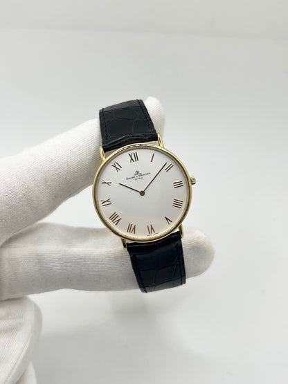 Montre Baume & Mercier Classima 15172A en or jaune, équipée d’un mouvement à quartz et d’un boîtier de 33 mm. Son cadran blanc à chiffres romains apporte une allure élégante et intemporelle, tandis que le verre saphir assure sa protection. Ce modèle est monté sur un bracelet noir en cuir de crocodile avec boucle ardillon en acier. Une montre raffinée, idéale pour une tenue chic et élégante, en très bon état.