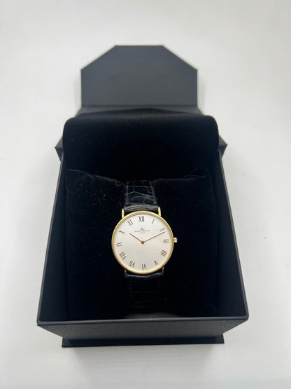 Montre Baume & Mercier Classima 15172A en or jaune, équipée d’un mouvement à quartz et d’un boîtier de 33 mm. Son cadran blanc à chiffres romains apporte une allure élégante et intemporelle, tandis que le verre saphir assure sa protection. Ce modèle est monté sur un bracelet noir en cuir de crocodile avec boucle ardillon en acier. Une montre raffinée, idéale pour une tenue chic et élégante, en très bon état.