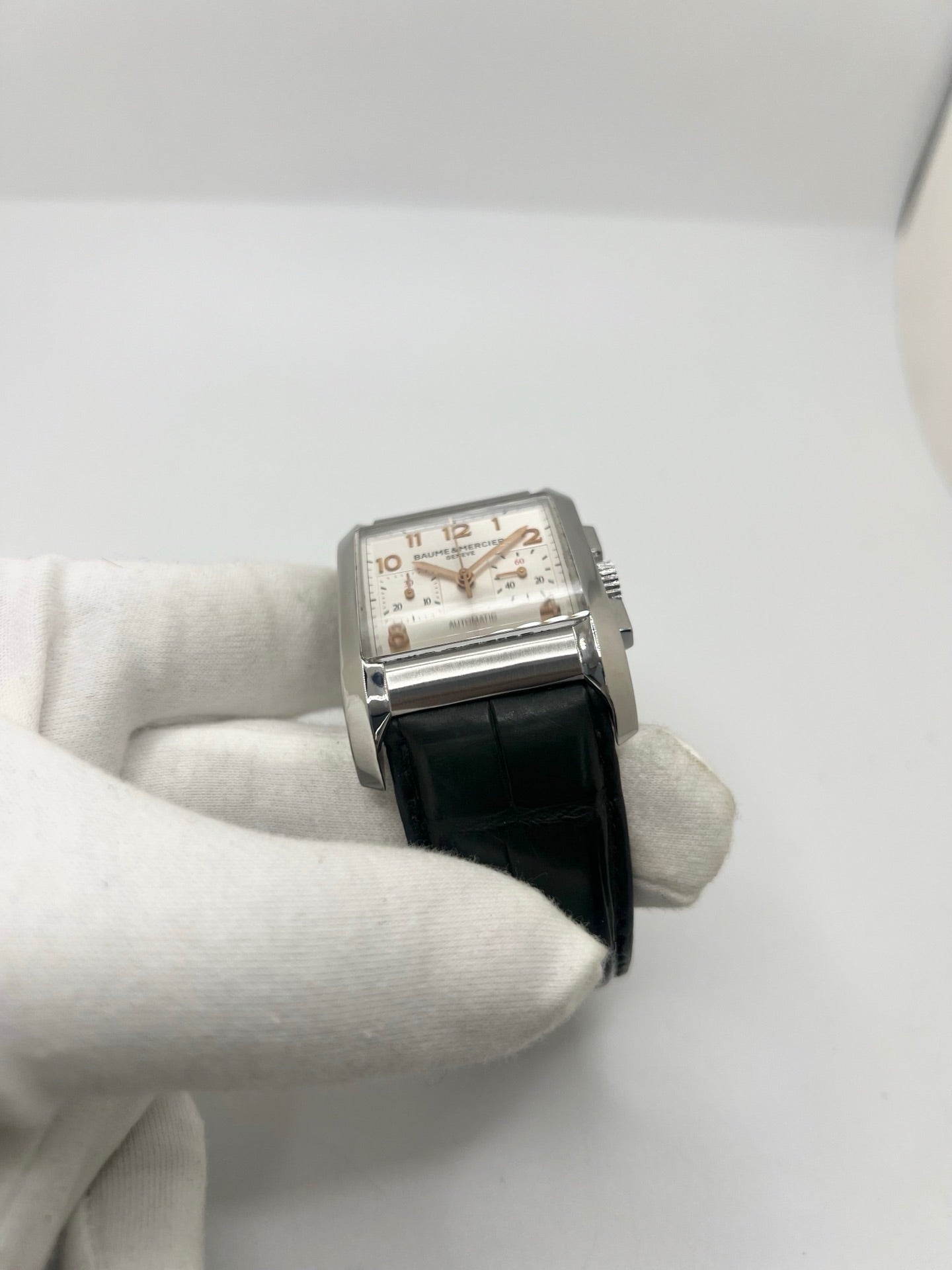 Montre Baume & Mercier Hampton réf. 65698, modèle automatique pour homme ou unisexe. Boîtier en acier de 34,5 mm avec verre saphir résistant aux rayures. Cadran argent avec index en chiffres arabes, offrant une lecture élégante et classique. Bracelet en cuir vert avec boucle déployante en acier. Fonction chronographe et date. Montre de luxe d’occasion en très bon état, avec légères traces d’usure. Révisée le 24 juin 2026 en interne. Livrée sans coffret ni papiers. Disponible à Paris.