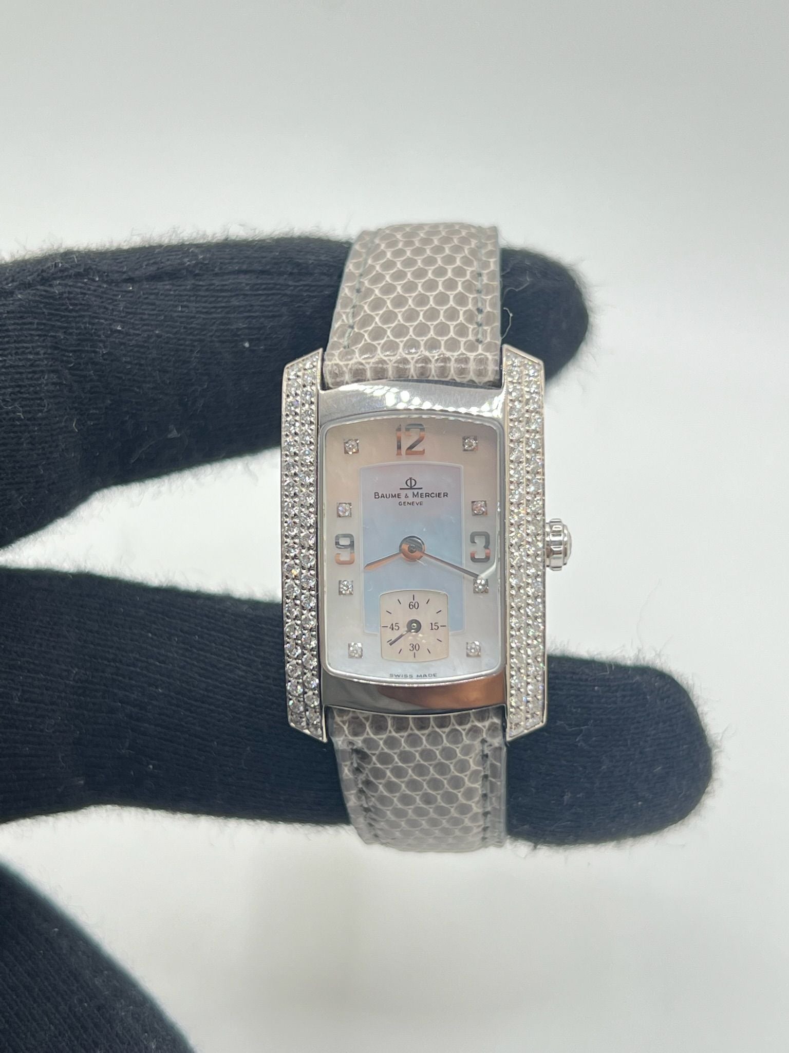 Cette Baume & Mercier Hampton Milleis incarne l’élégance intemporelle avec son boîtier rectangulaire en or blanc 18K, sublimé de diamants. Son cadran aux lignes Art déco reflète l’excellence horlogère suisse. Montée sur un bracelet en cuir de lézard (non d’origine), elle est livrée avec son coffret d’origine. Entièrement révisée en juin 2025 et garantie un an, cette pièce rare allie luxe, raffinement et fiabilité, parfaite pour les passionnés de belles montres.
