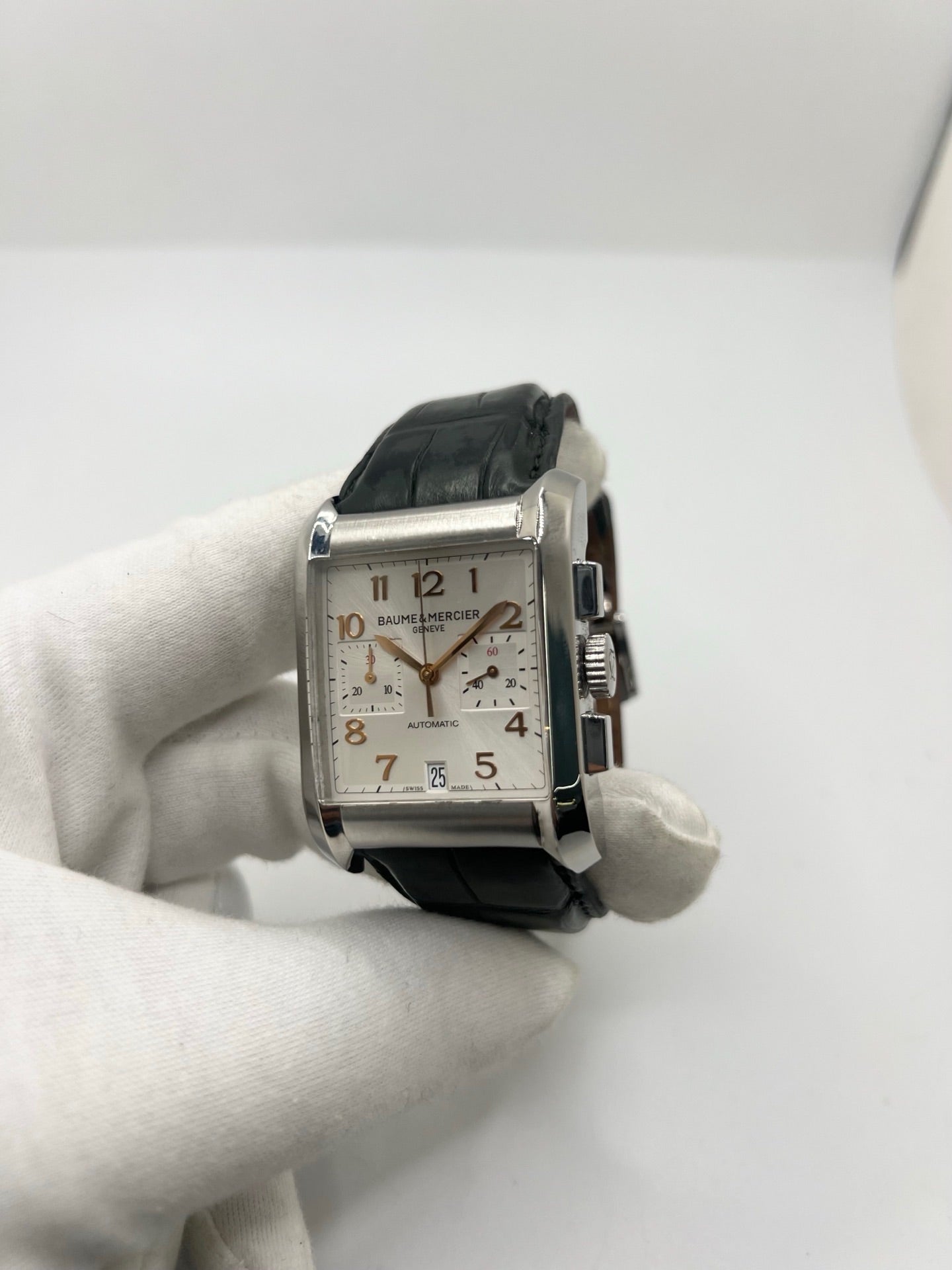 Montre Baume & Mercier Hampton réf. 65698, modèle automatique pour homme ou unisexe. Boîtier en acier de 34,5 mm avec verre saphir résistant aux rayures. Cadran argent avec index en chiffres arabes, offrant une lecture élégante et classique. Bracelet en cuir vert avec boucle déployante en acier. Fonction chronographe et date. Montre de luxe d’occasion en très bon état, avec légères traces d’usure. Révisée le 24 juin 2026 en interne. Livrée sans coffret ni papiers. Disponible à Paris.