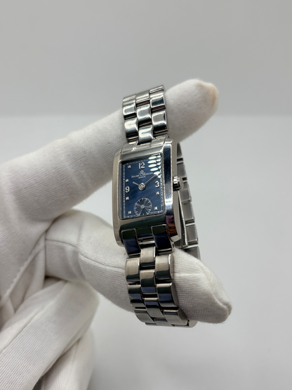 Montre Baume & Mercier Hampton MV045139 équipée d’un mouvement à quartz et d’un boîtier rectangulaire en acier de 20 × 34 mm. Son cadran bleu à chiffres arabes est protégé par un verre saphir. Cette montre Baume & Mercier Hampton est montée sur un bracelet en acier avec boucle déployante double plis. Élégante et contemporaine, elle séduit par ses lignes raffinées et son format rectangulaire emblématique, idéale pour un style chic au quotidien.