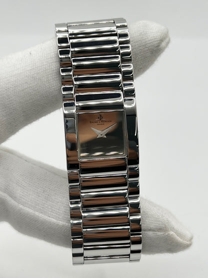 Montre femme Baume & Mercier Catwalk MV045219 à quartz, avec boîtier rectangulaire en acier de 24 x 21 mm, cadran argenté sans chiffres et bracelet en acier à boucle déployante double plis. Son verre saphir et son design élégant en font une montre raffinée et intemporelle. Cette Baume & Mercier Catwalk d’occasion est en très bon état, avec de légères rayures non perceptibles au toucher. Révisée en interne le 21 octobre 2026, elle est disponible à Paris sans coffret ni papiers d’origine.