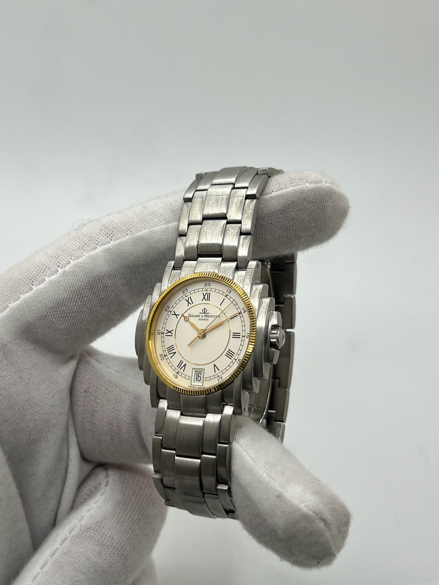 Montre Baume & Mercier 5136.018.3 pour homme/unisexe, boîtier 34 mm en or et acier, cadran blanc à chiffres romains, mouvement quartz précis. Verre saphir résistant aux rayures, bracelet en acier avec boucle double plis. Fonction date. Montre d’occasion en très bon état avec papiers d’origine, élégante et intemporelle.