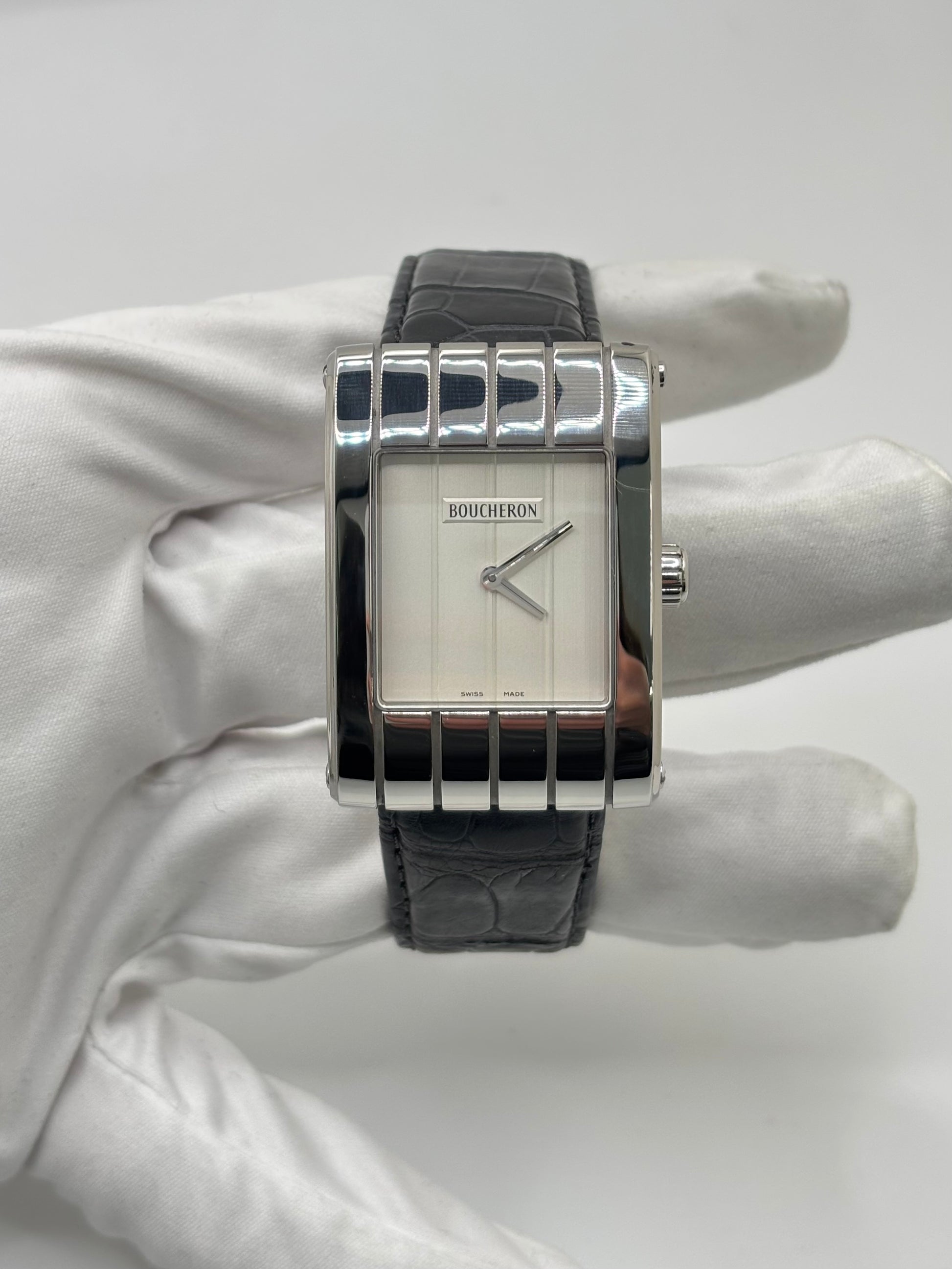 Montre Boucheron Reflet Icare Parallèle en acier, équipée d’un mouvement quartz précis. Boîtier rectangulaire 28 x 40 mm avec verre saphir et cadran blanc épuré. Bracelet en cuir de crocodile noir avec boucle ardillon en acier. Modèle homme/unisexe au design élégant et intemporel. Montre d’occasion en très bon état, présentant de légères traces d’usure non perceptibles au toucher, révisée en avril 2026, idéale pour amateurs d’horlogerie et de pièces de luxe.