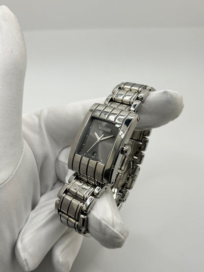 Montre Boucheron Reflet Icare Parallèle en acier, boîtier rectangulaire de 28 x 40 mm avec verre saphir et cadran gris à index bâtons. Équipée d’un mouvement quartz fiable et d’un bracelet en acier avec boucle double déployante. Fonction date discrète. Modèle élégant au design graphique emblématique de la collection Reflet. Montre d’occasion en très bon état, présentant de légères micro-rayures, révisée en interne, sans coffret ni papiers d’origine.