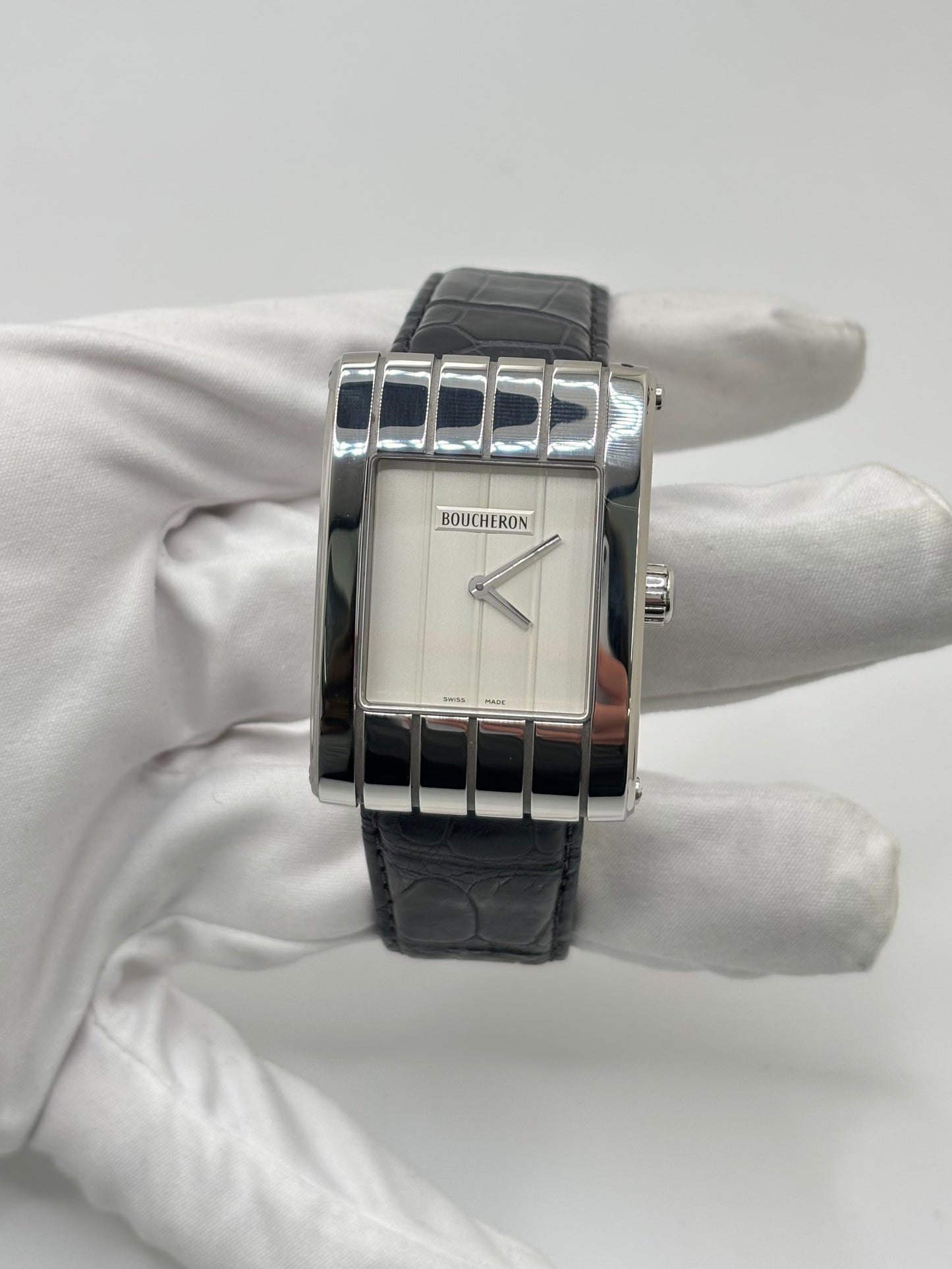 Montre Boucheron Reflet Icare Parallèle en acier, équipée d’un mouvement quartz précis. Boîtier rectangulaire 28 x 40 mm avec verre saphir et cadran blanc épuré. Bracelet en cuir de crocodile noir avec boucle ardillon en acier. Modèle homme/unisexe au design élégant et intemporel. Montre d’occasion en très bon état, présentant de légères traces d’usure non perceptibles au toucher, révisée en avril 2026, idéale pour amateurs d’horlogerie et de pièces de luxe.