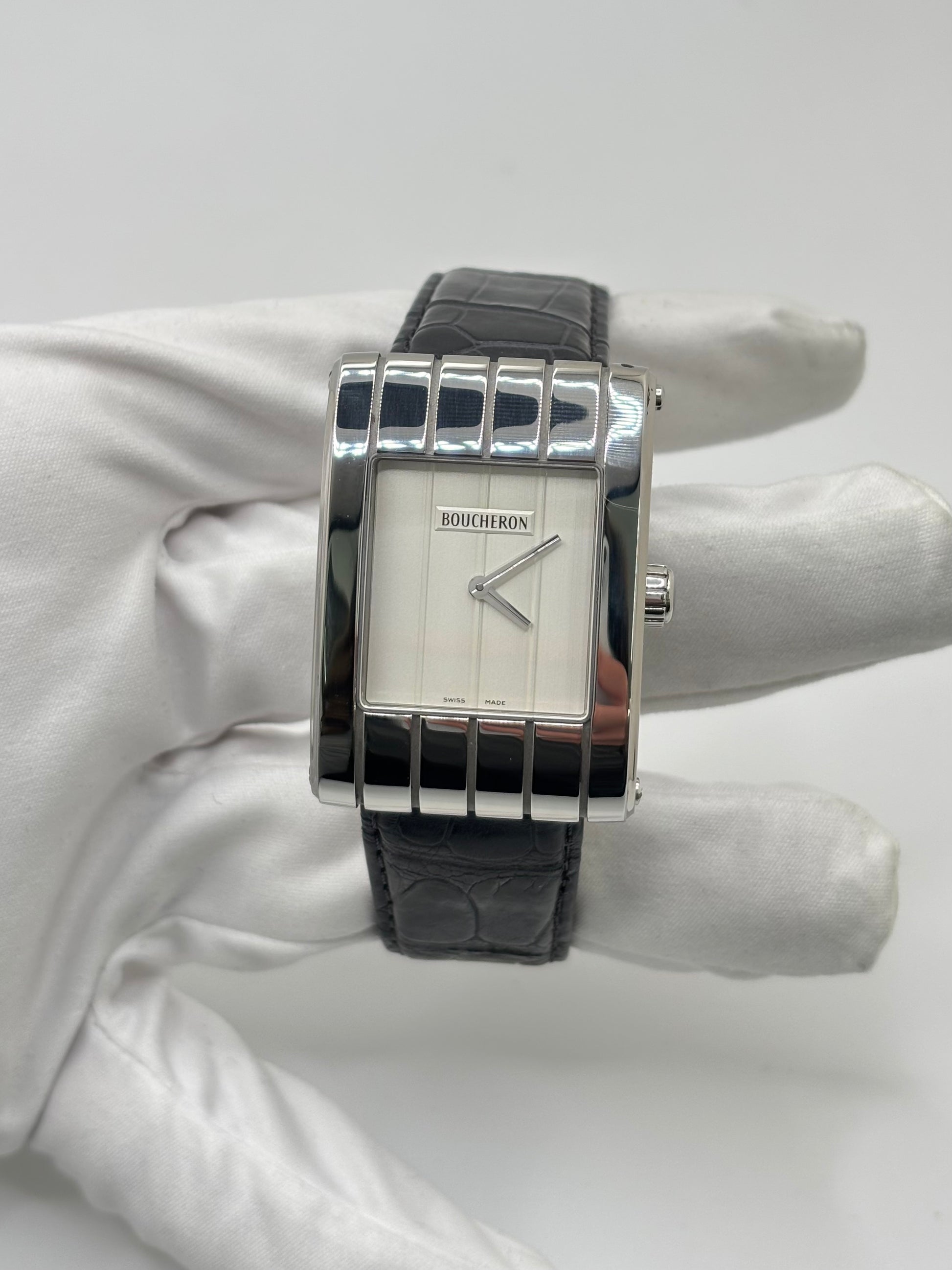 Montre Boucheron Reflet Icare Parallèle en acier, équipée d’un mouvement quartz précis. Boîtier rectangulaire 28 x 40 mm avec verre saphir et cadran blanc épuré. Bracelet en cuir de crocodile noir avec boucle ardillon en acier. Modèle homme/unisexe au design élégant et intemporel. Montre d’occasion en très bon état, présentant de légères traces d’usure non perceptibles au toucher, révisée en avril 2026, idéale pour amateurs d’horlogerie et de pièces de luxe.