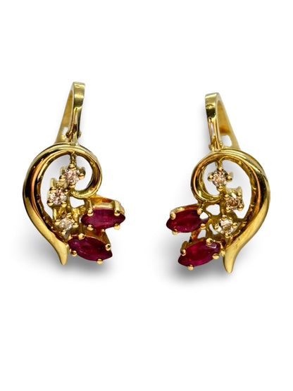 Boucles d’oreilles en or jaune 18K ornées de rubis totalisant 0,30 ct et de diamants de 0,12 ct. Élégantes et raffinées, elles associent l’intensité rouge des rubis à l’éclat subtil des diamants. Cette paire intemporelle sublime toutes les tenues et constitue un bijou précieux, parfait pour offrir ou compléter une collection de joaillerie fine.