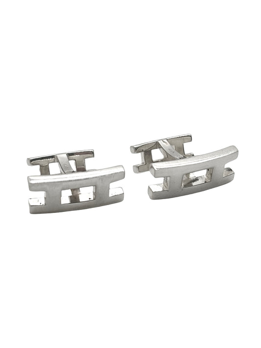 Boutons de manchettes Hermès en argent 925 au style élégant et intemporel. Cette paire raffinée en argent massif séduit par ses finitions soignées et son design sophistiqué caractéristique du savoir-faire Hermès. Accessoires de luxe parfaits pour compléter un costume, une tenue habillée ou une cérémonie. Boutons de manchettes précieux alliant distinction, élégance masculine et qualité joaillière dans un esprit chic et contemporain.