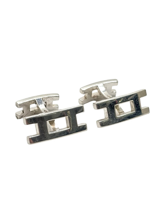 Boutons de manchettes Hermès en argent 925 au style élégant et intemporel. Cette paire raffinée en argent massif séduit par ses finitions soignées et son design sophistiqué caractéristique du savoir-faire Hermès. Accessoires de luxe parfaits pour compléter un costume, une tenue habillée ou une cérémonie. Boutons de manchettes précieux alliant distinction, élégance masculine et qualité joaillière dans un esprit chic et contemporain.