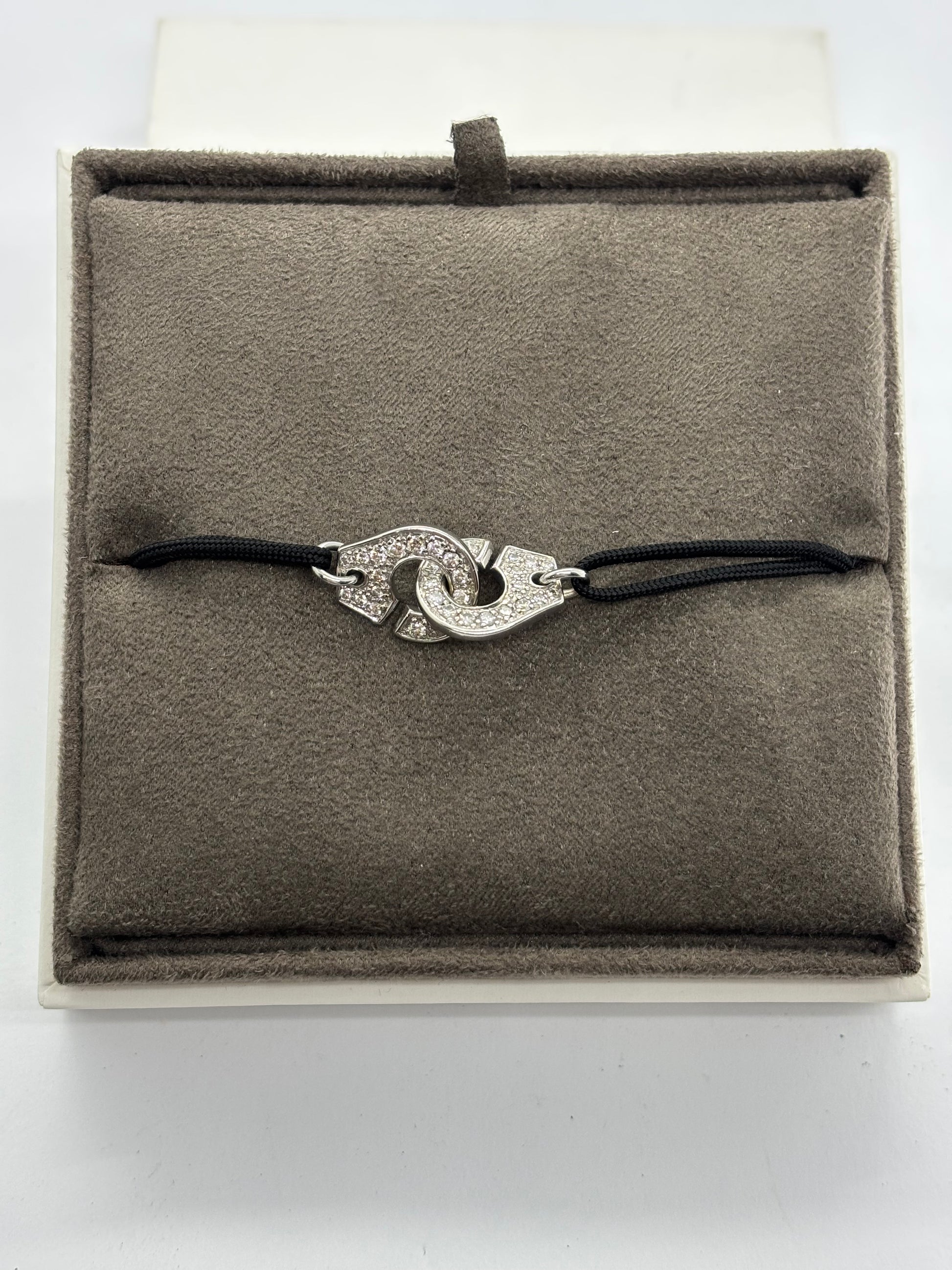 Bracelet Dinh Van Menottes en or blanc serti de diamants, symbole d’union et de modernité. Son design épuré et contemporain mêle éclat du métal précieux et brillance des pierres. Une création élégante et intemporelle, parfaite pour sublimer le poignet avec raffinement et discrétion.