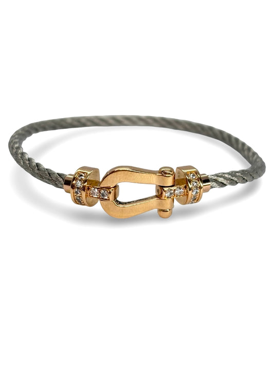 Icône de la Maison Fred, le bracelet Force 10 en or rose et diamants 0,12 ct allie élégance et modernité. Son câble tressé et sa boucle sertie de diamants reflètent un savoir-faire joaillier unique. Symbole de force et de raffinement, il sublime le poignet avec éclat et sophistication.