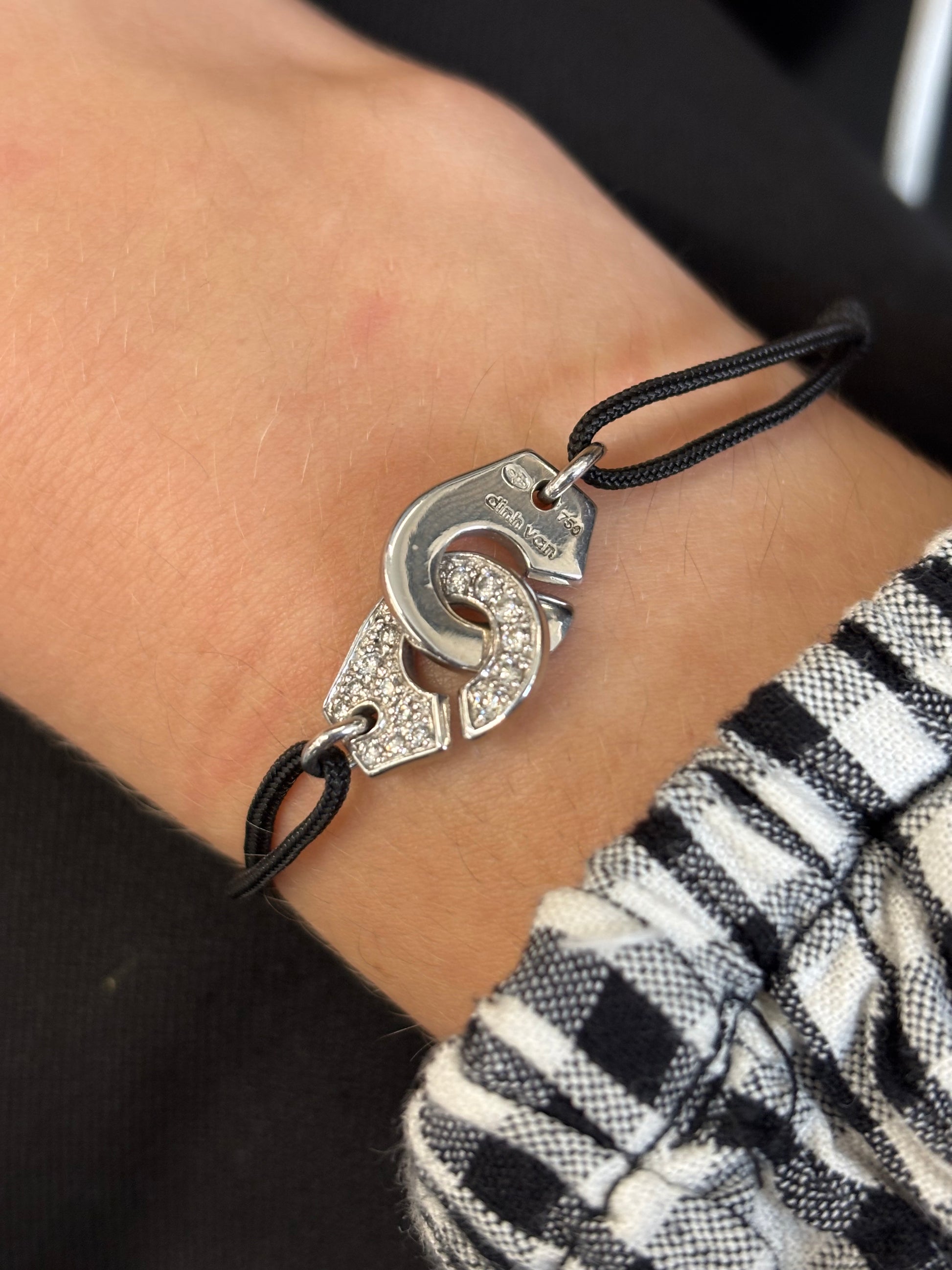 Bracelet Dinh Van Menottes en or blanc serti de diamants, symbole d’union et de modernité. Son design épuré et contemporain mêle éclat du métal précieux et brillance des pierres. Une création élégante et intemporelle, parfaite pour sublimer le poignet avec raffinement et discrétion.