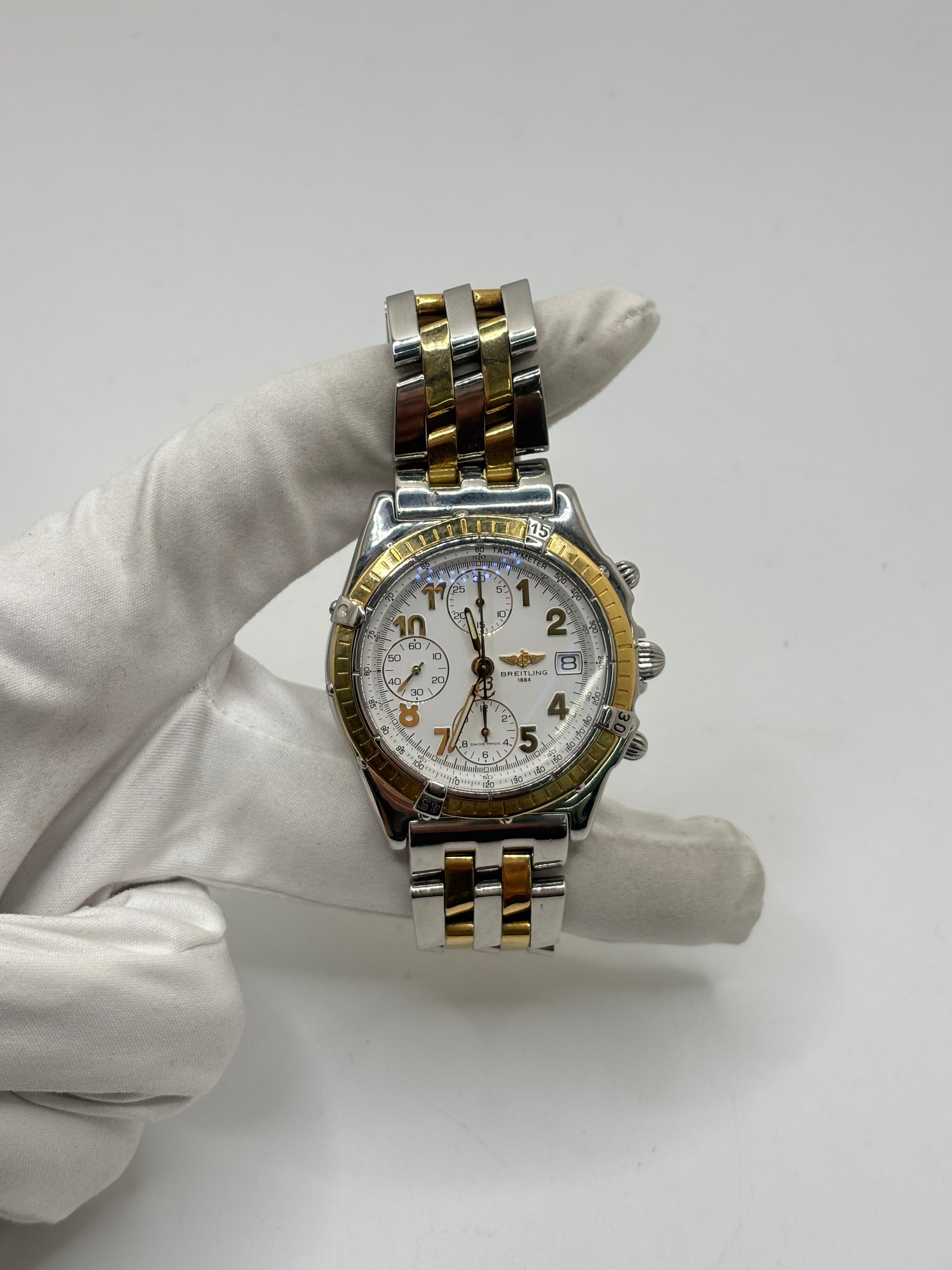 Montre Breitling Chronomat B13050.1 en or et acier avec boîtier de 39 mm, cadran blanc à chiffres arabes, verre saphir et mouvement automatique Breitling 13 basé sur l'ETA Valjoux 7750. Ce chronographe est équipé d'un bracelet en or et acier avec boucle déployante d'origine. Révisée, en excellent état et garantie 1 an, cette montre de luxe suisse allie élégance intemporelle, précision horlogère et finitions haut de gamme.