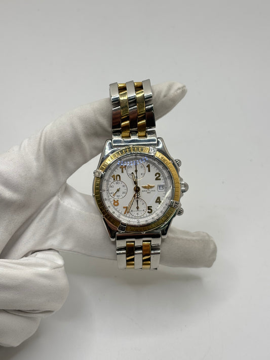 Montre Breitling Chronomat B13050.1 en or et acier avec boîtier de 39 mm, cadran blanc à chiffres arabes, verre saphir et mouvement automatique Breitling 13 basé sur l'ETA Valjoux 7750. Ce chronographe est équipé d'un bracelet en or et acier avec boucle déployante d'origine. Révisée, en excellent état et garantie 1 an, cette montre de luxe suisse allie élégance intemporelle, précision horlogère et finitions haut de gamme.
