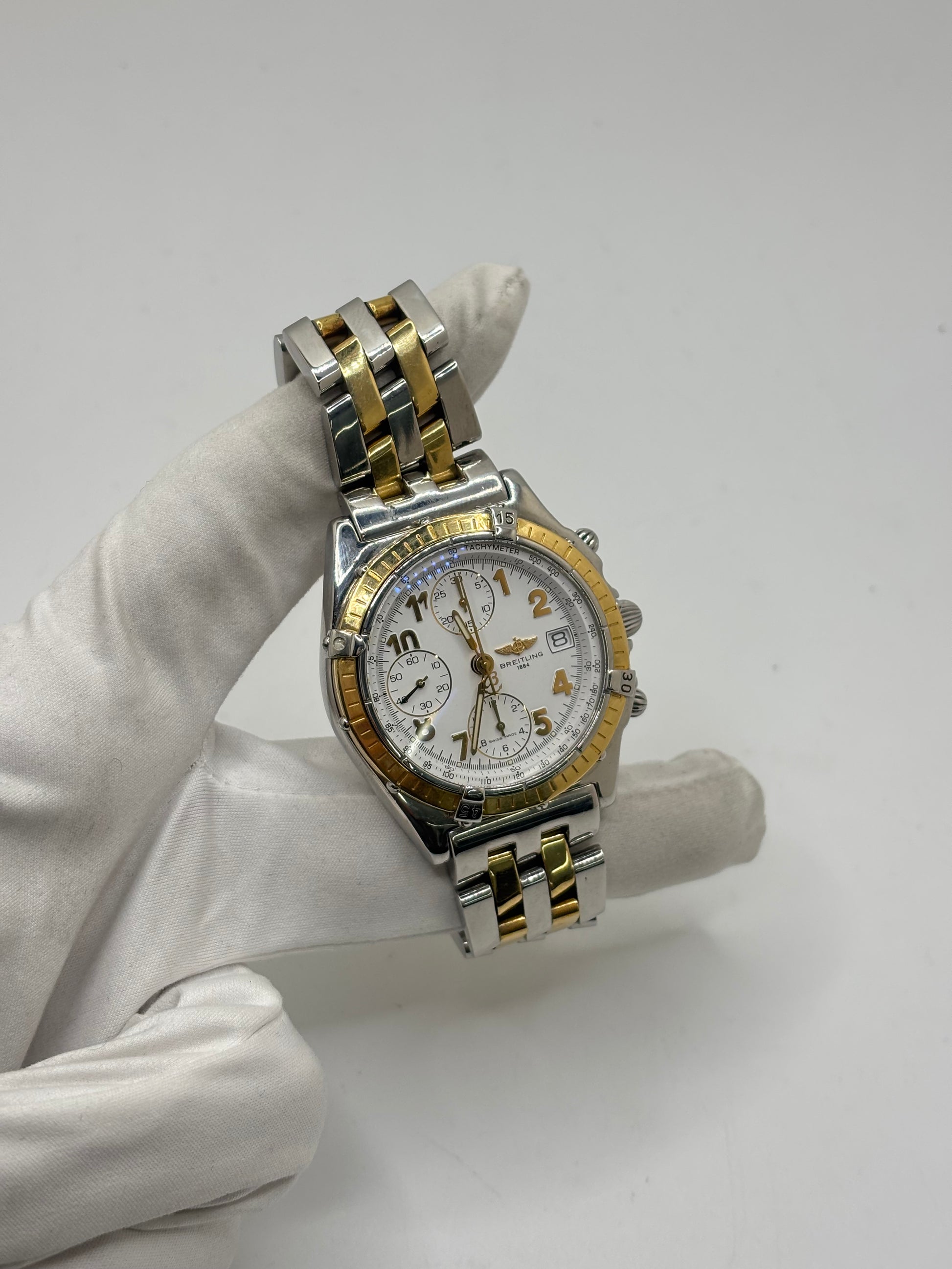 Montre Breitling Chronomat B13050.1 en or et acier avec boîtier de 39 mm, cadran blanc à chiffres arabes, verre saphir et mouvement automatique Breitling 13 basé sur l'ETA Valjoux 7750. Ce chronographe est équipé d'un bracelet en or et acier avec boucle déployante d'origine. Révisée, en excellent état et garantie 1 an, cette montre de luxe suisse allie élégance intemporelle, précision horlogère et finitions haut de gamme.