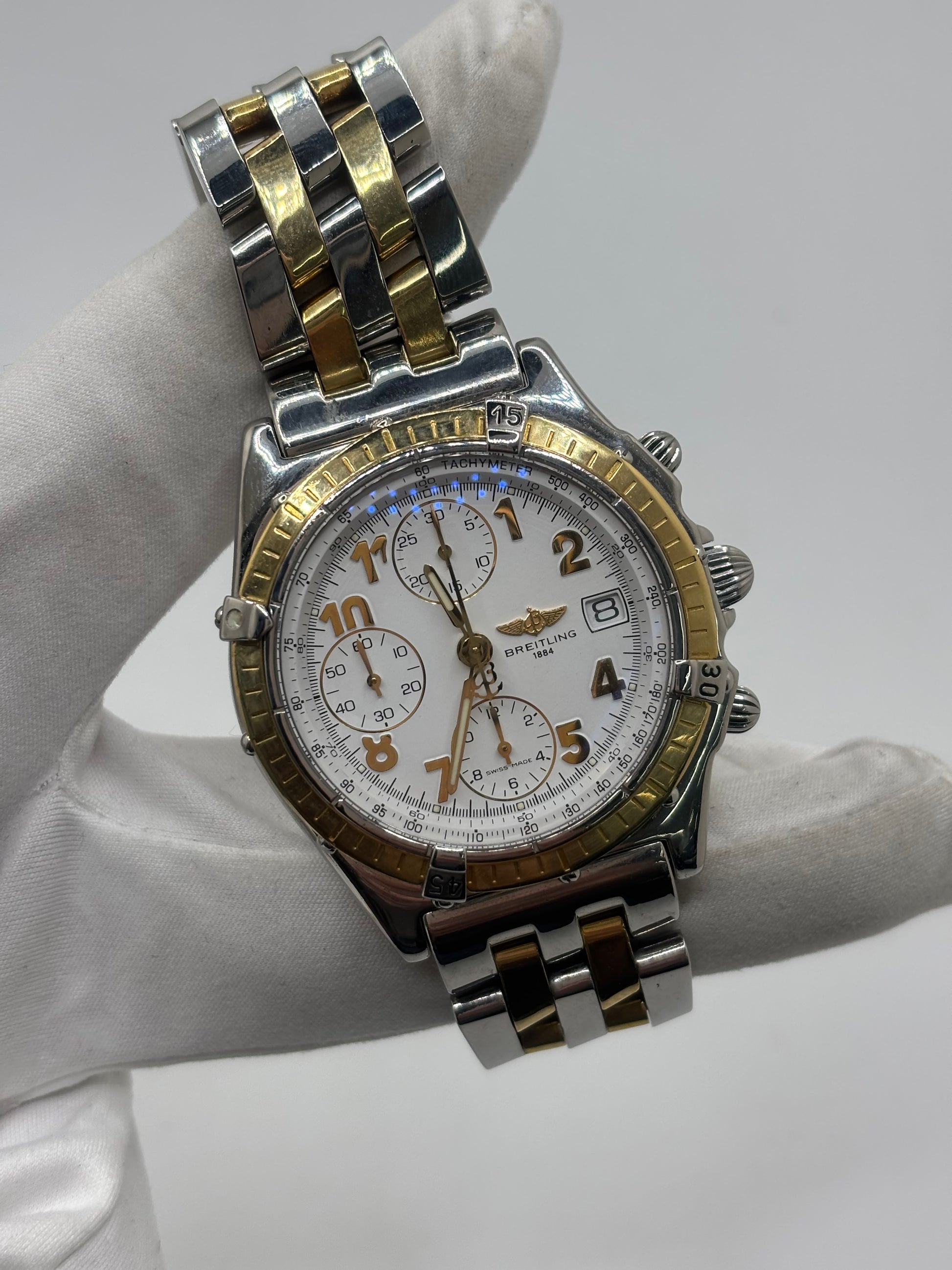 Montre Breitling Chronomat B13050.1 en or et acier avec boîtier de 39 mm, cadran blanc à chiffres arabes, verre saphir et mouvement automatique Breitling 13 basé sur l'ETA Valjoux 7750. Ce chronographe est équipé d'un bracelet en or et acier avec boucle déployante d'origine. Révisée, en excellent état et garantie 1 an, cette montre de luxe suisse allie élégance intemporelle, précision horlogère et finitions haut de gamme.